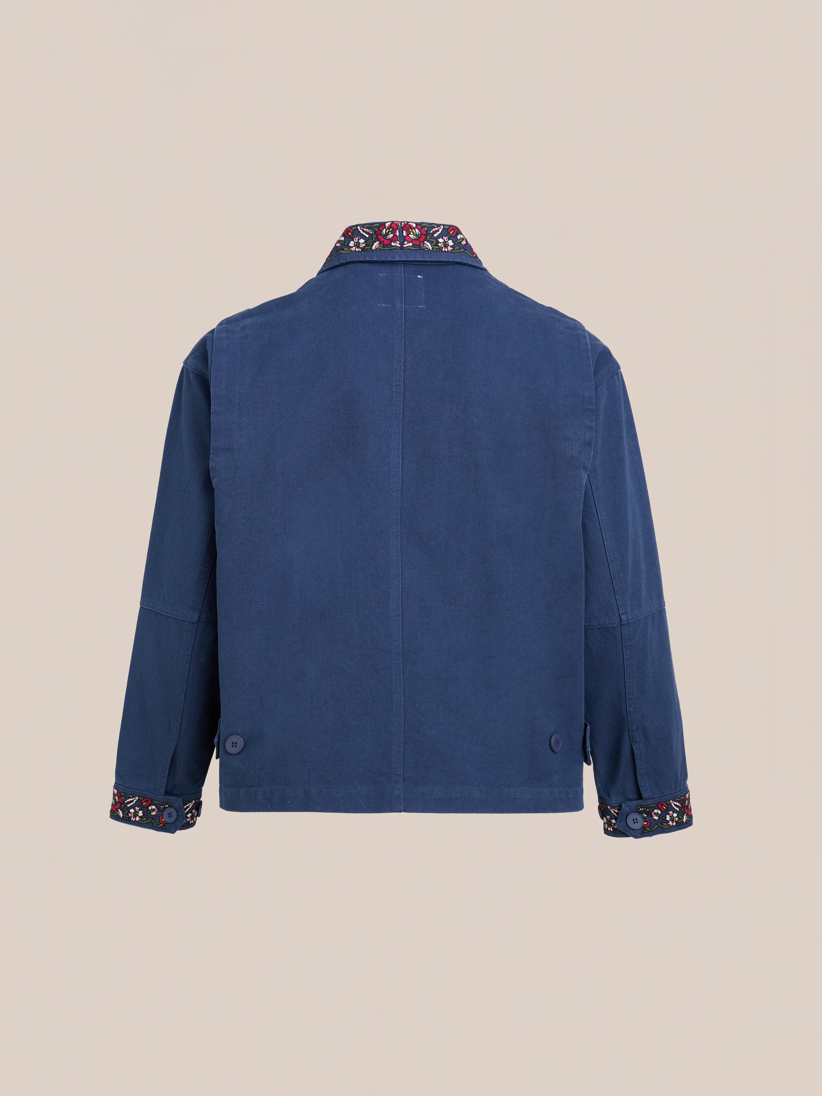 The Found Horse Equine Work Jacket is shown from the back in blue, with racing colours on the patterned trim of the collar and sleeve cuffs.