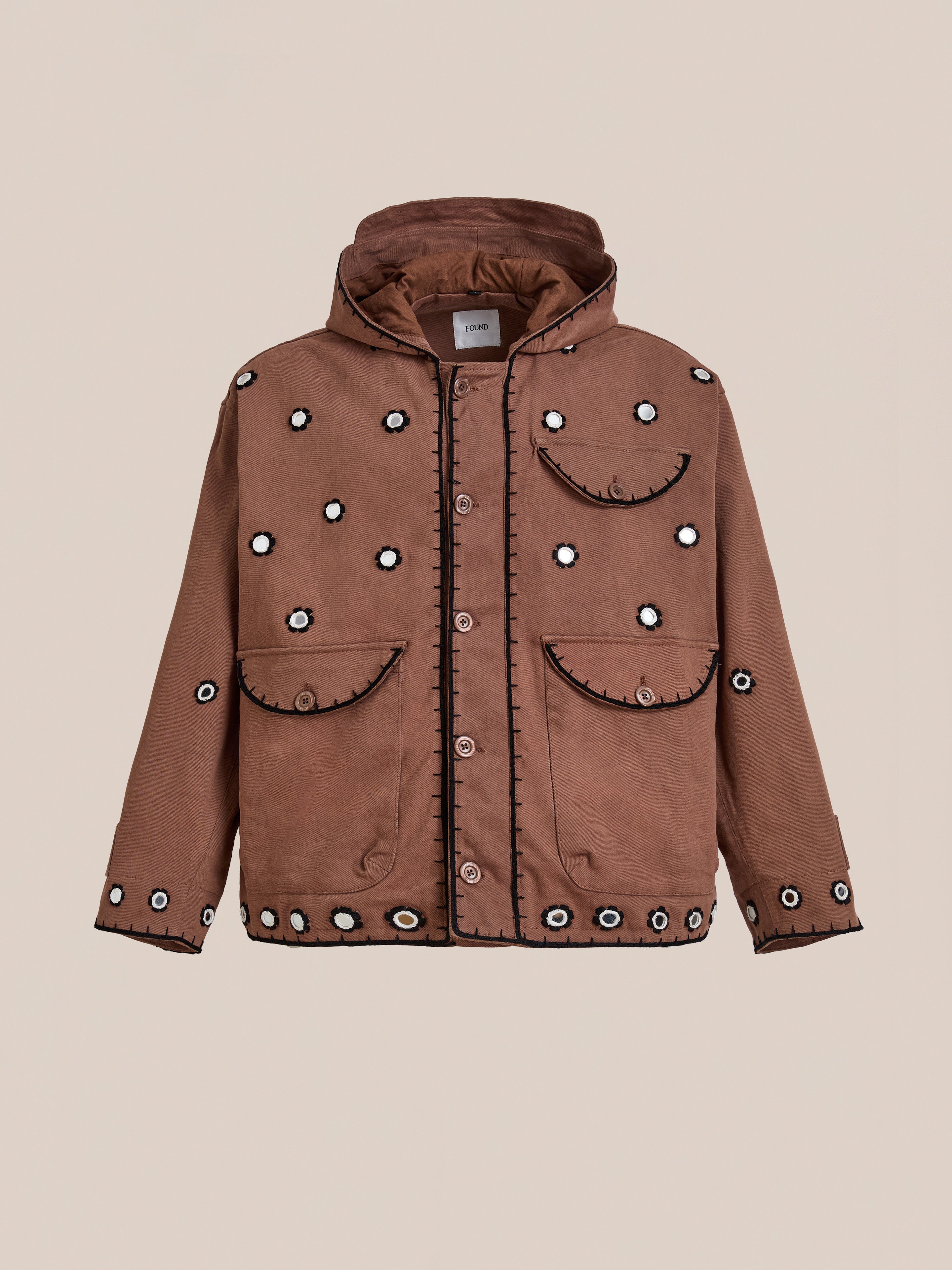 The FOUND Hand Embroidered Hooded Mirror Anorak features button closure, four front pockets, and intricate white and black Sheesha Kari-inspired mirror embroidery on the front, sleeves, and pockets, shown against a plain background.