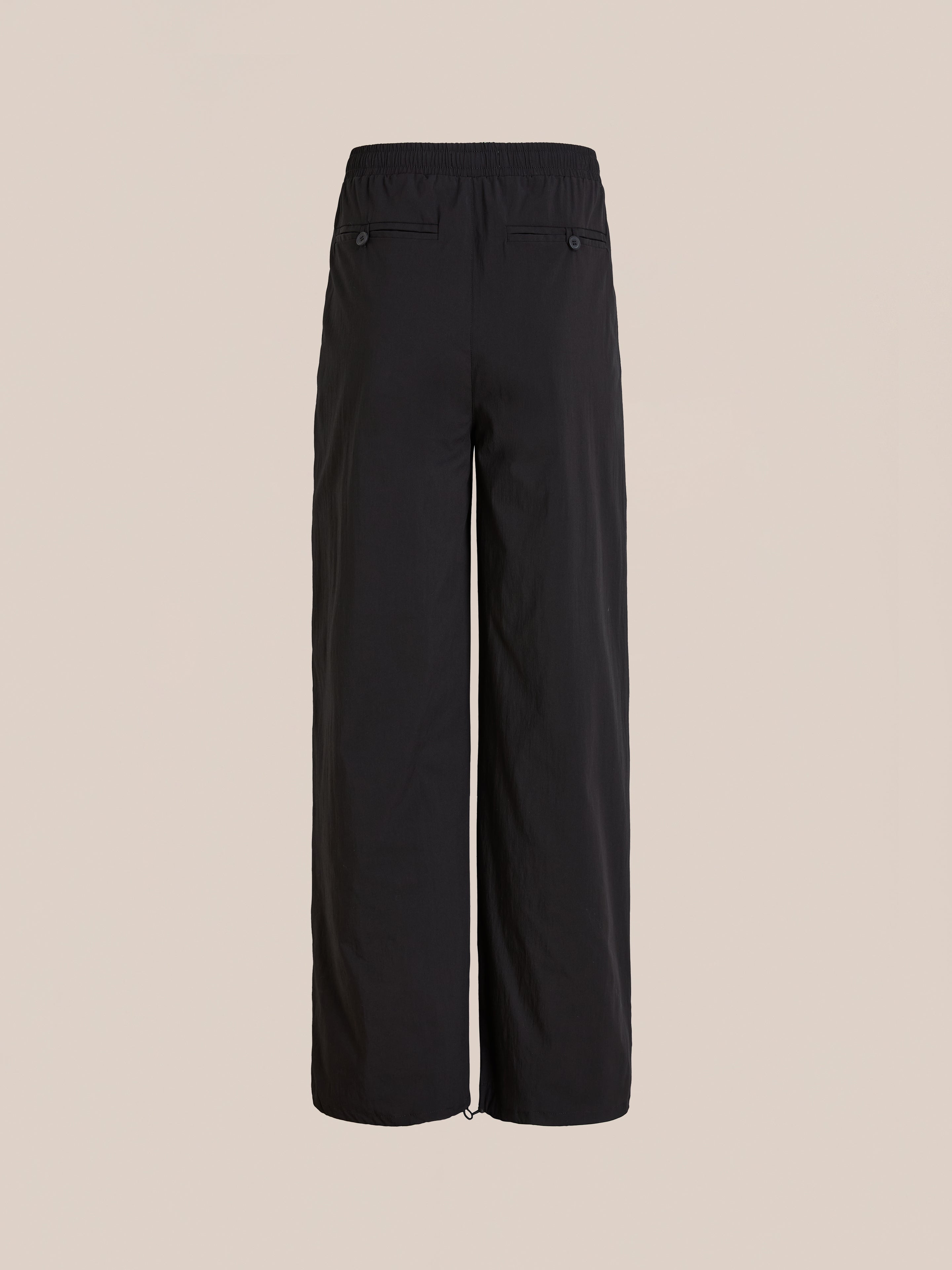 The Found Arena Stripe Track Pants feature a black wide-leg design, adjustable waistband, and two back pockets for versatile unisex sportswear style, shown against a plain beige background.