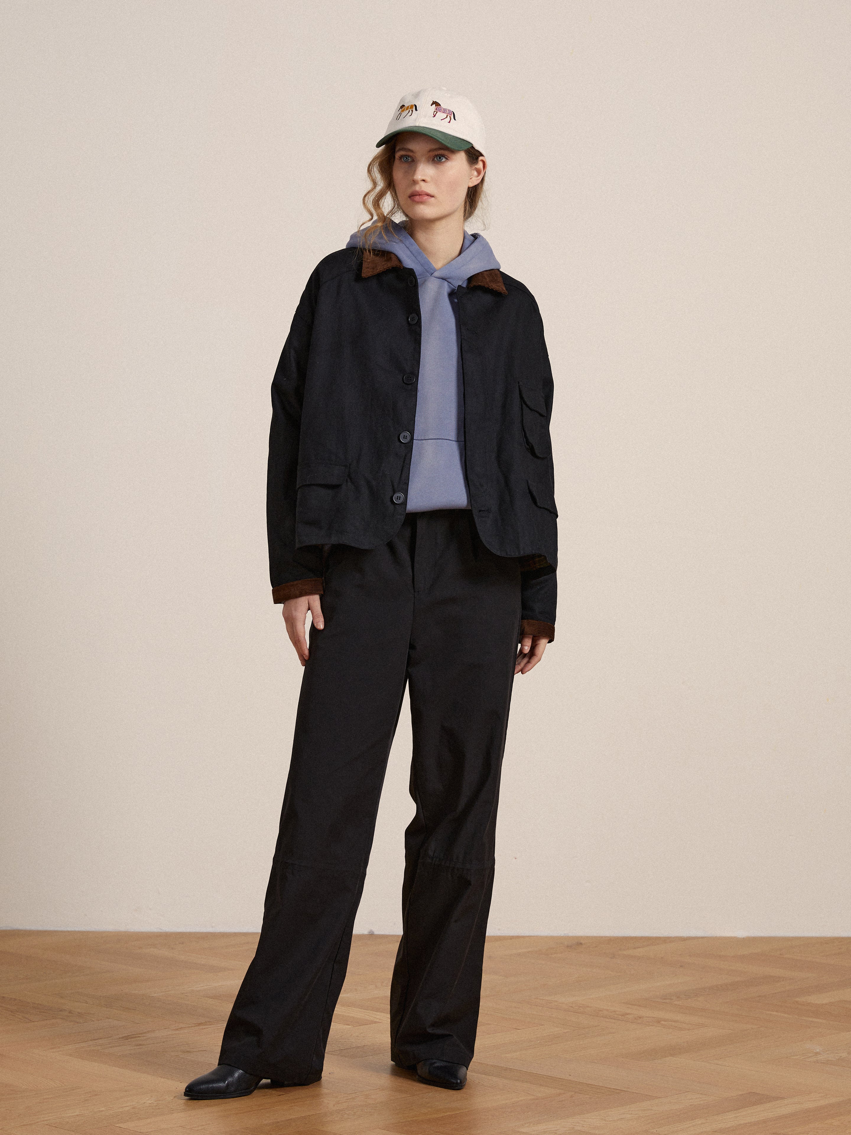 A woman wearing a faded black Found Infinity Hoodie and hat.