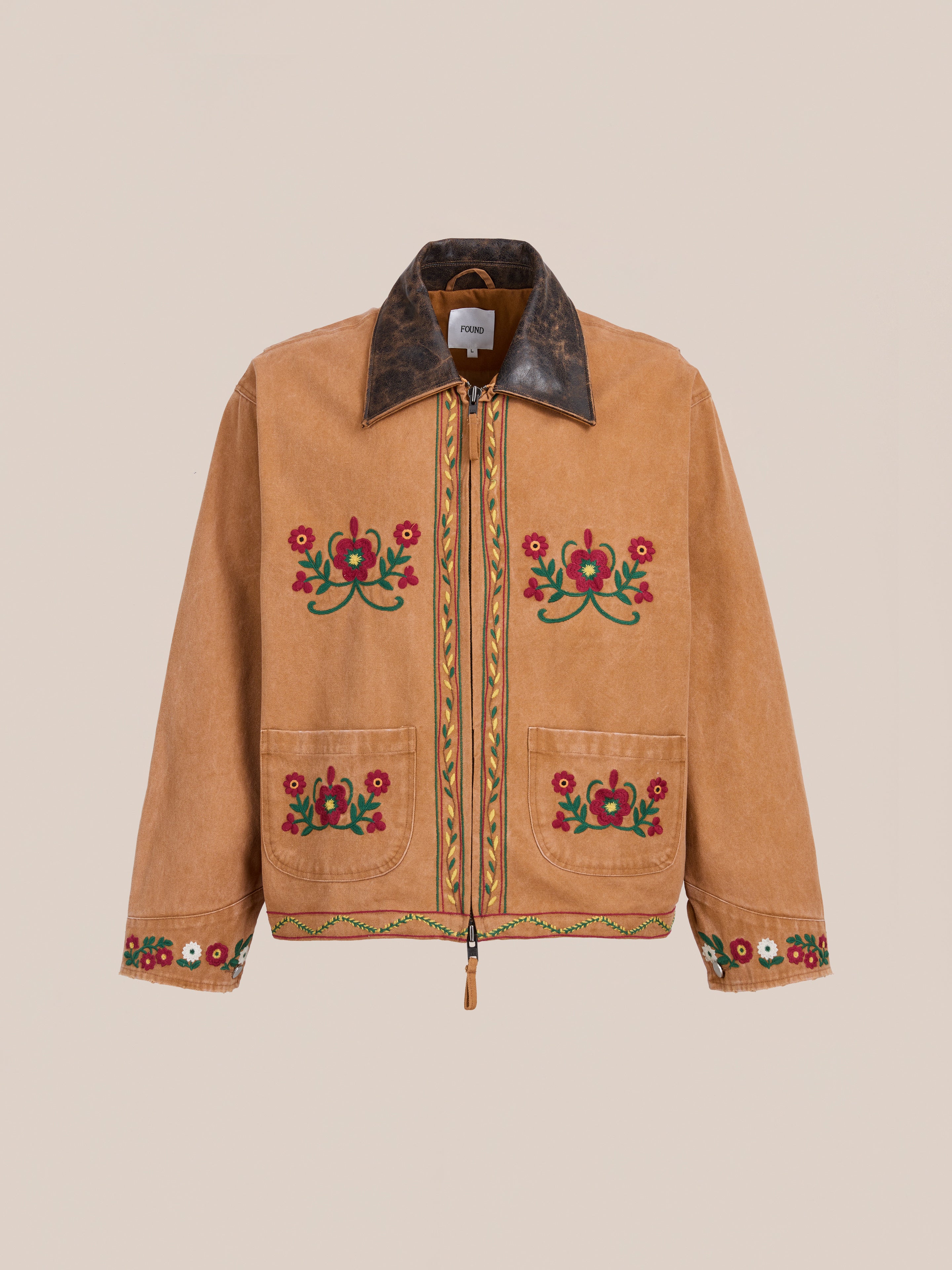 The Rosette Canvas Work Jacket by Found features a tan vintage brown color, dark brown collar, red and green floral embroidery on the front, sleeves, and hem, two front pockets, and a zip closure for classic style.
