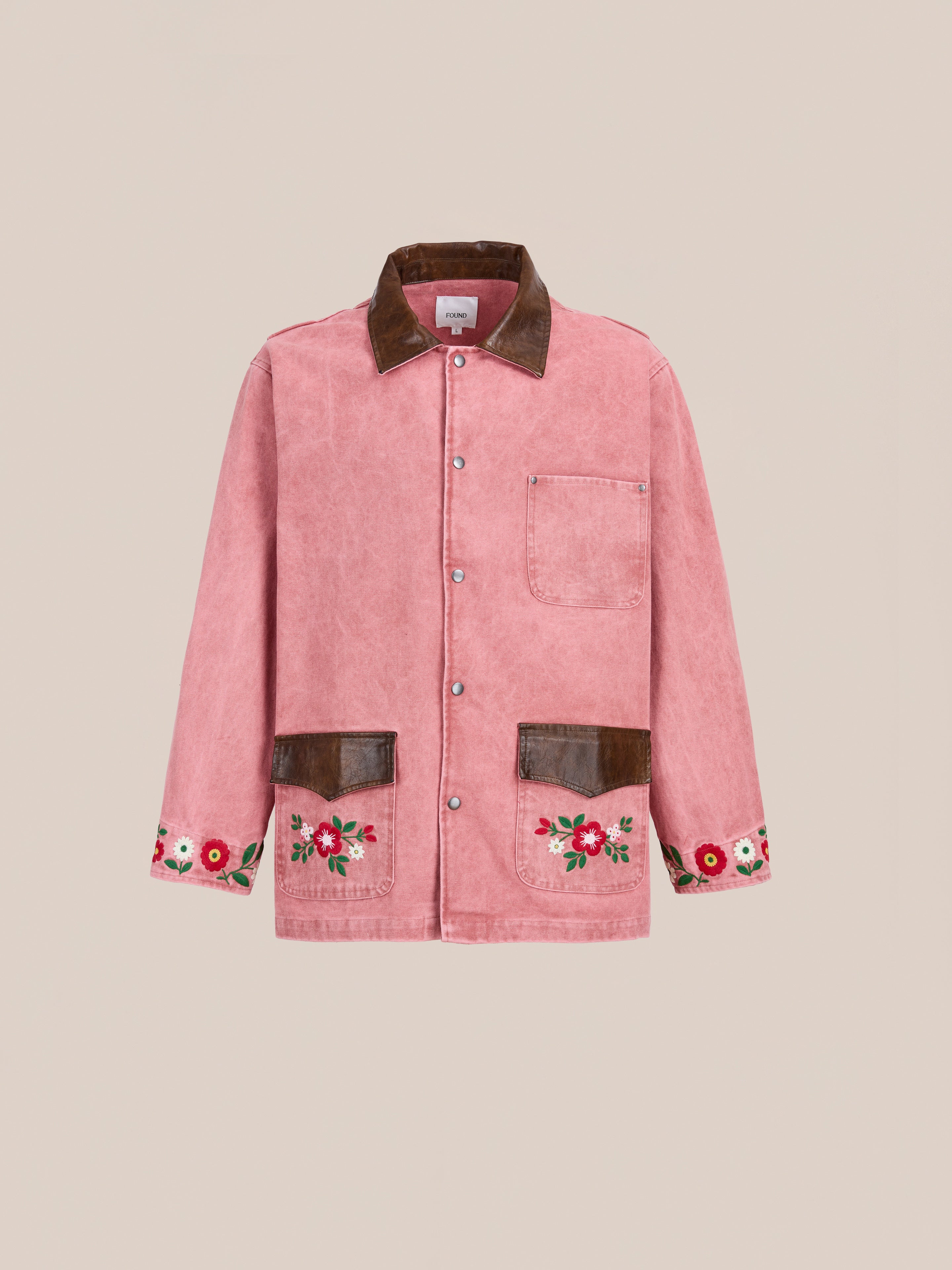 The Found Canvas Embroidered Barn Jacket features vintage-washed pink corduroy, a brown collar, snap buttons, and floral embroidery on the pockets and cuffs, shown against a plain background.