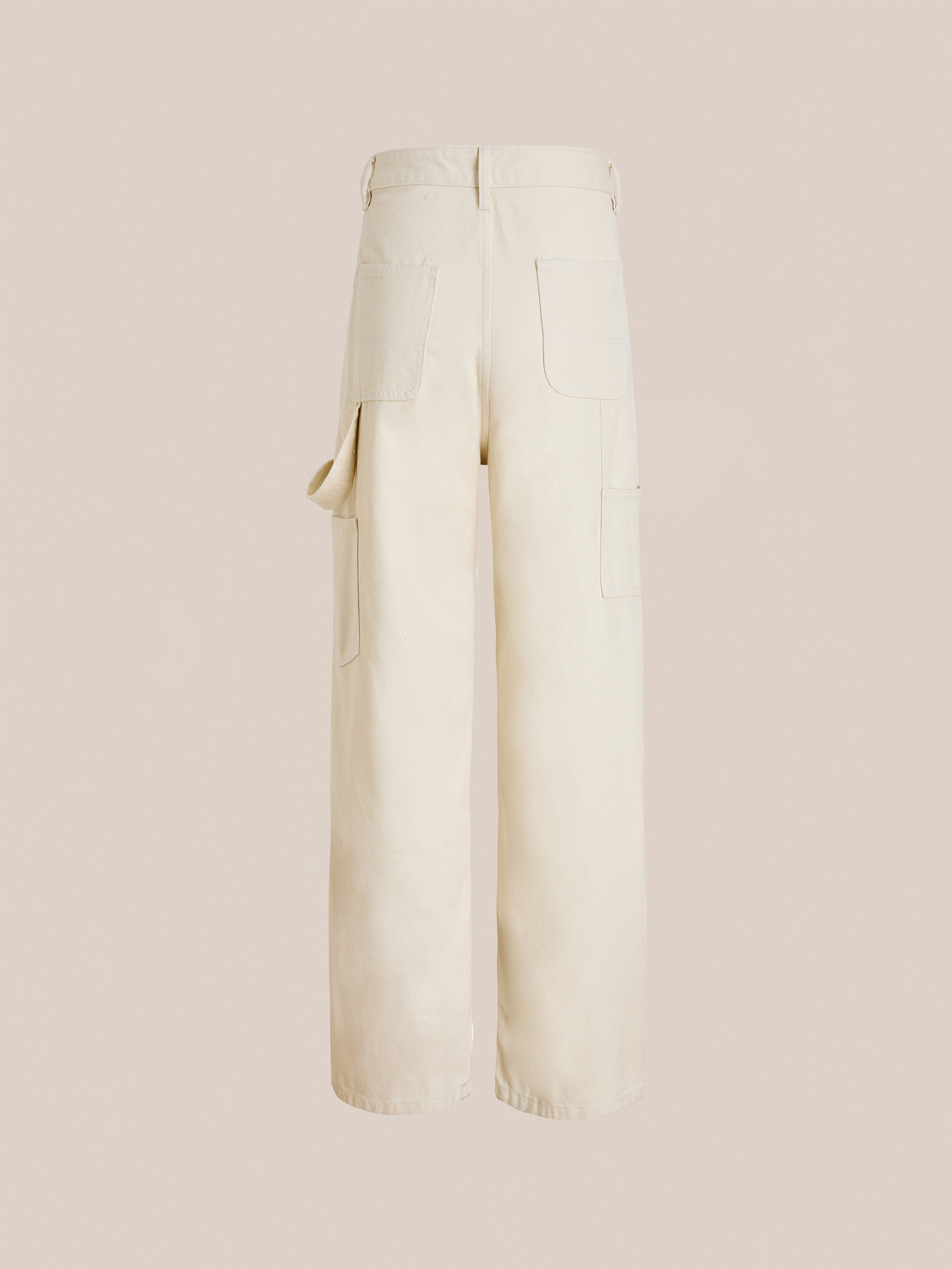 FOUND’s Tapestry Carpenter Canvas Pants in beige feature wide legs, large patch pockets, and a side loop. Shown from the back, their unisex relaxed fit ensures comfort and versatile style for any wardrobe.