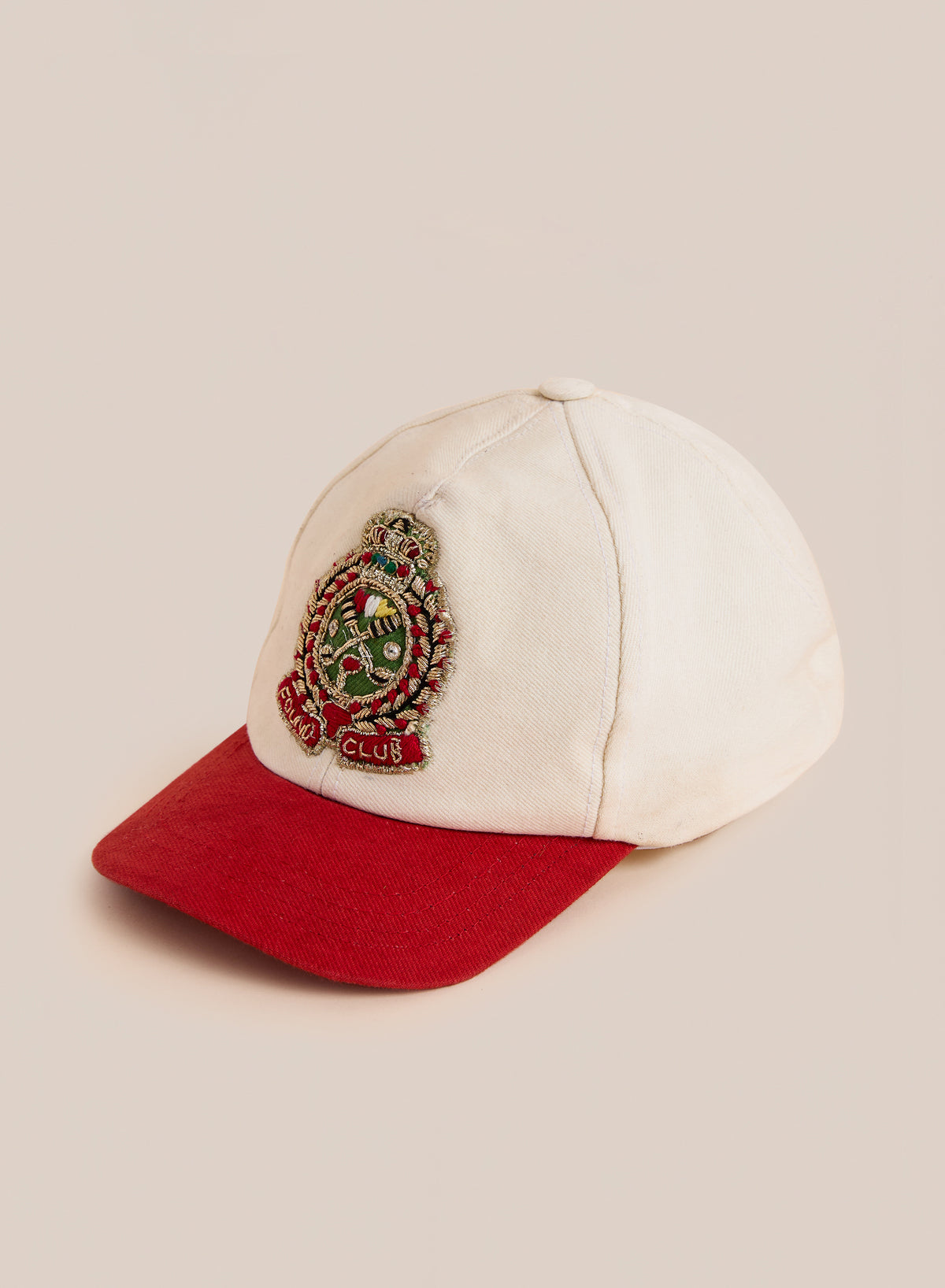 The Found Club Patch Cap features a red brim and embroidered crest on beige, offering classic heritage sportswear style.