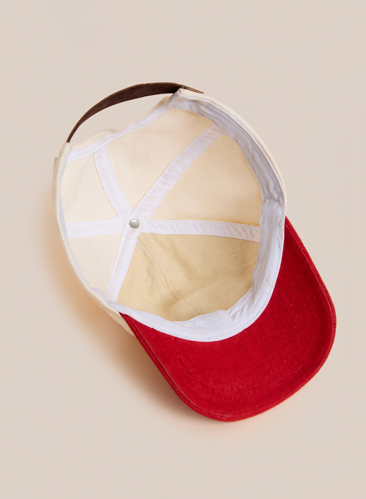 The Found Club Patch Cap is shown upside down on a neutral background, displaying its white inner lining and brown adjustable strap.