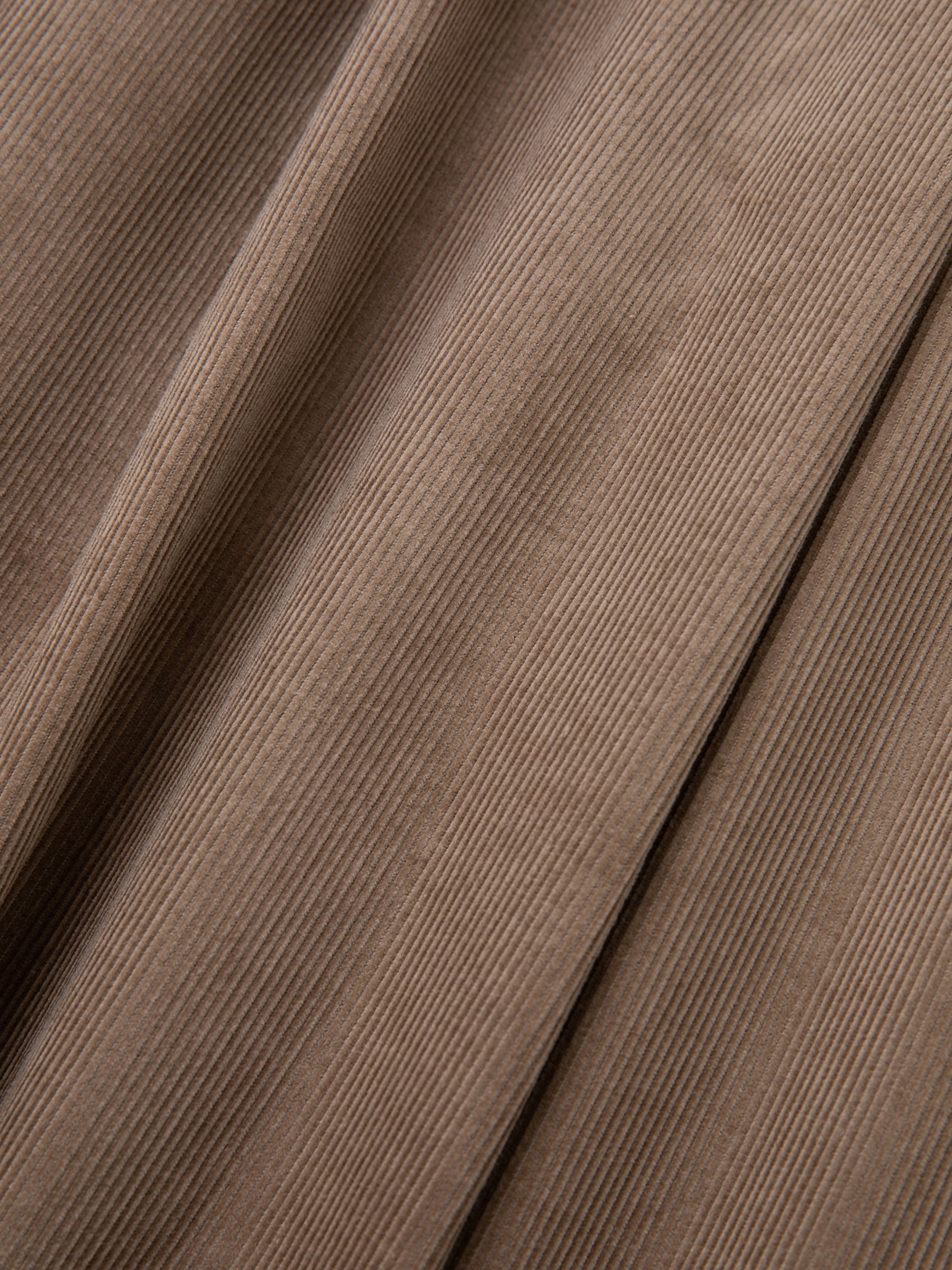 Close-up of FOUND's Corduroy Pleated Trousers in brown, showcasing the distinct vertical ridges characteristic of finely crafted fabric.