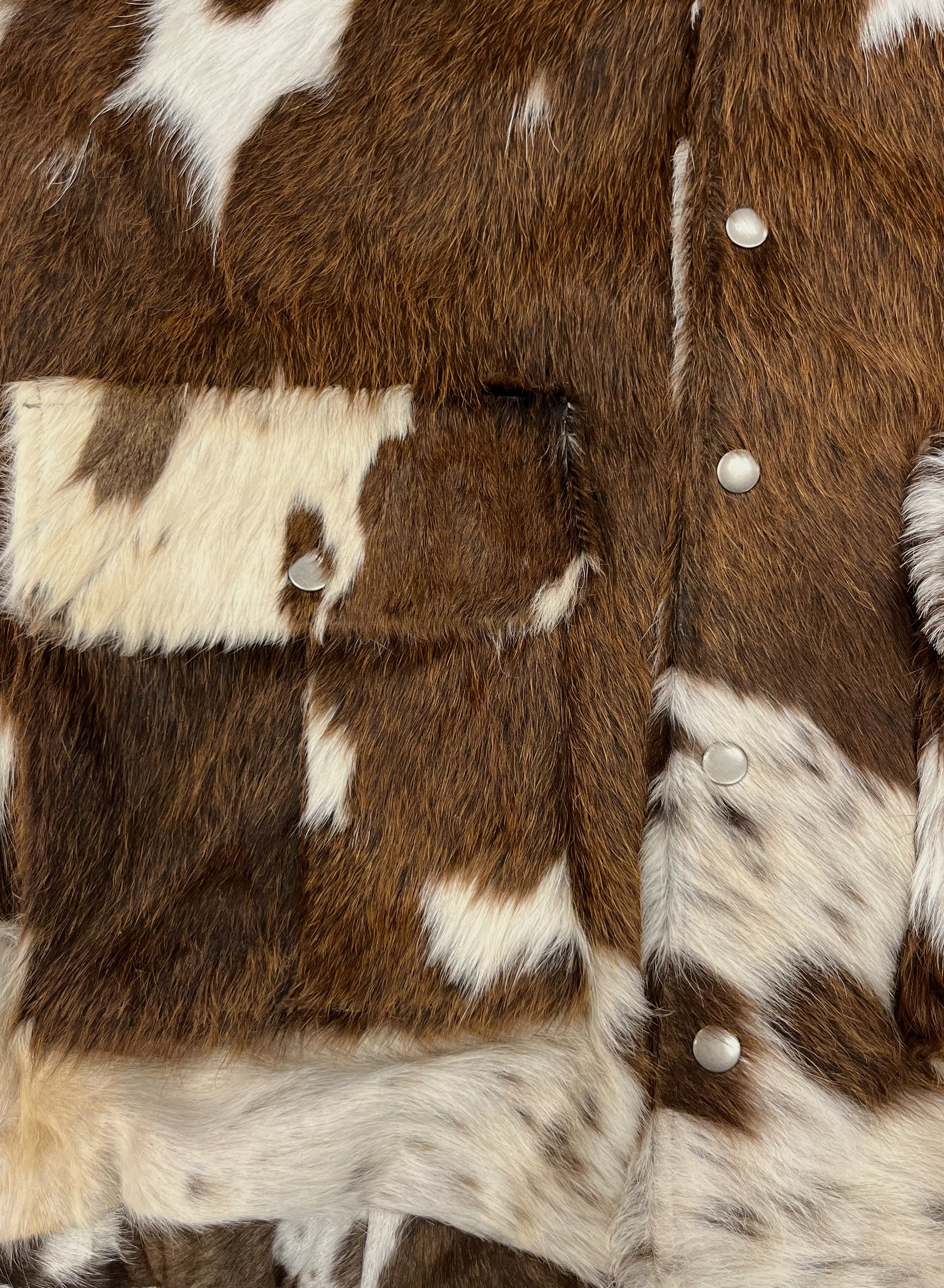 Close-up of the FOUND Cowhide Drover Hoodie, a unique unisex outerwear featuring brown and white faux fur, snap buttons, front pocket, and an eye-catching cowhide pattern.