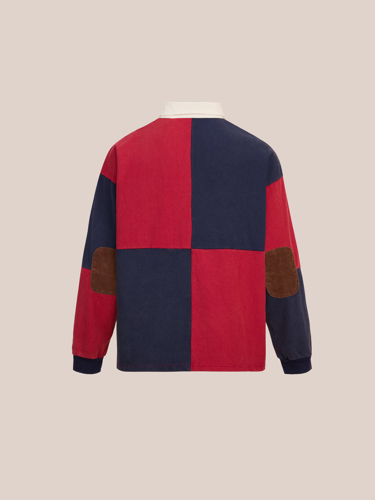 Back view of the FOUND Crestfield Rugby jacket, featuring bold red and navy blue color blocks, a classic white rugby shirt collar, and brown suede elbow patches, displayed against a plain beige background.