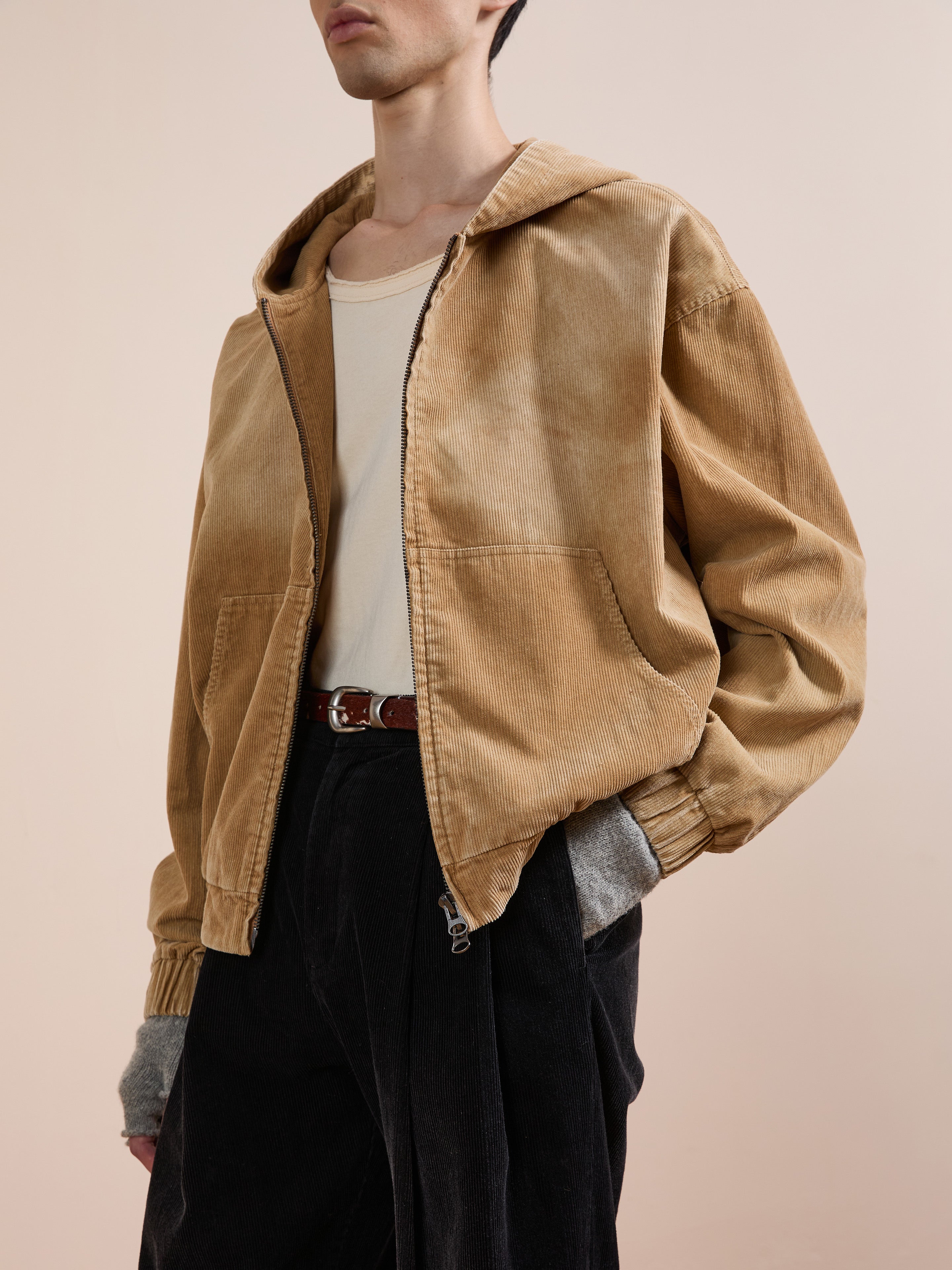 A person wears the FOUND Corduroy Zip Up Hoodie over a beige shirt, black pants, and gray fingerless gloves, standing against a plain light background.