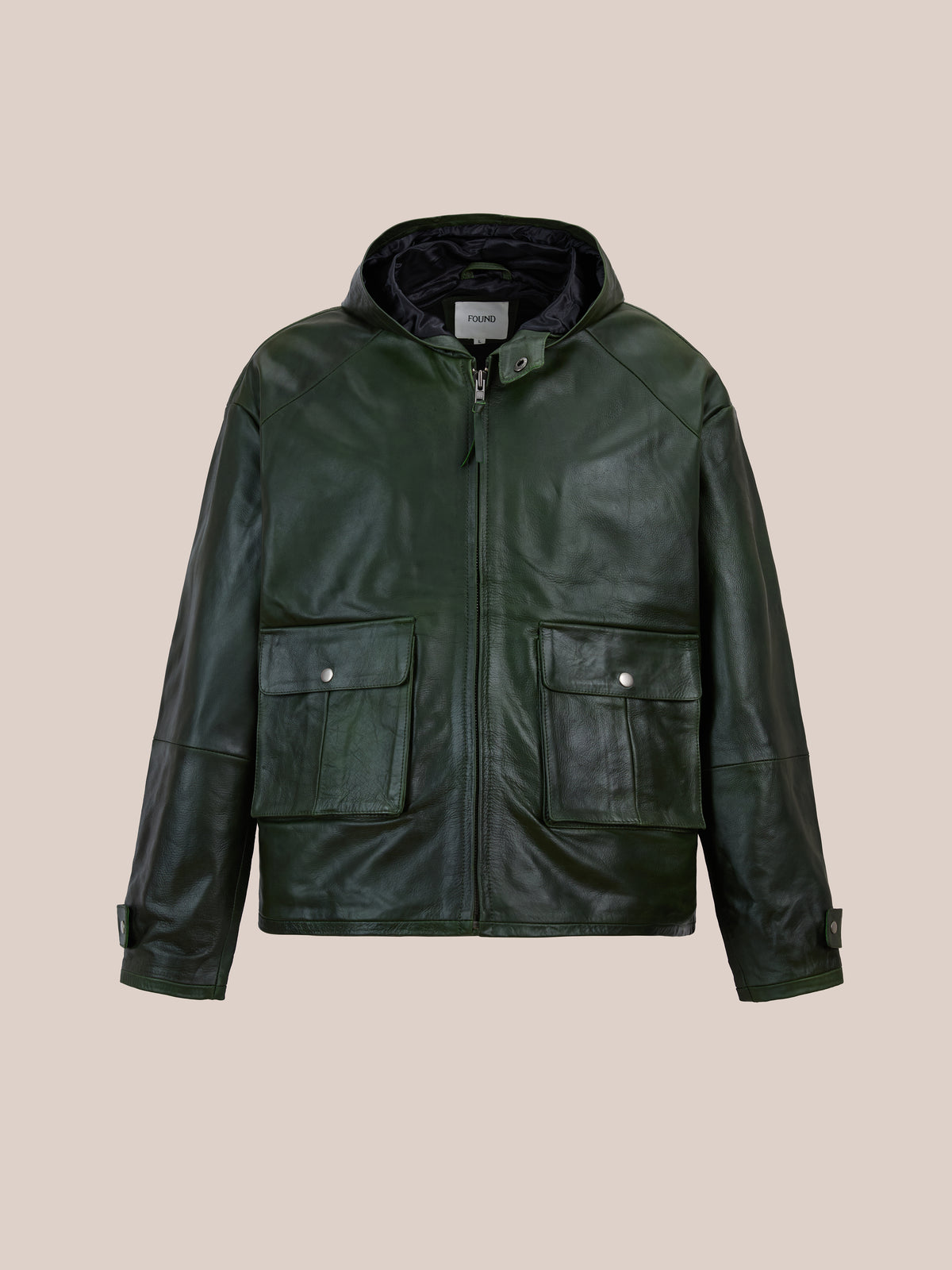 The FOUND Distressed Leather Pocket Hoodie features a dark green leather design with a hood, front zipper, two snap-flap pockets, and adjustable cuffs. Displayed against a plain beige background, this green leather jacket from FOUND fuses classic style with modern edge.