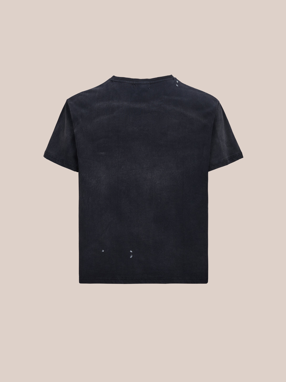 The FOUND Distressed Paint Tee, a unisex relaxed fit black short-sleeve t-shirt, is shown from the back and laid flat against a beige background.