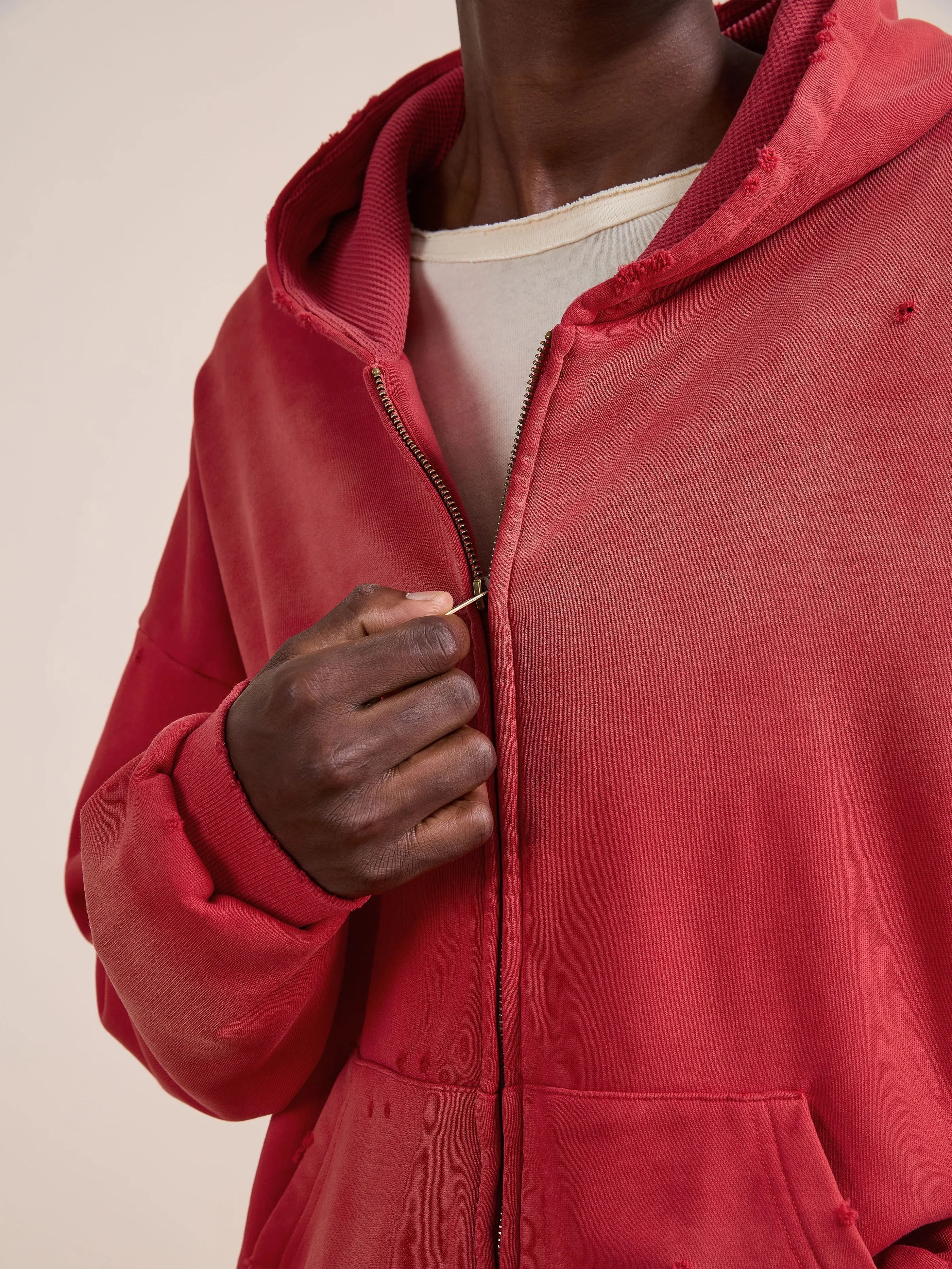A person is shown zipping up the FOUND Distressed Thermal Lined Zip Up Hoodie in red over a white shirt, with the focus on the torso and hand.
