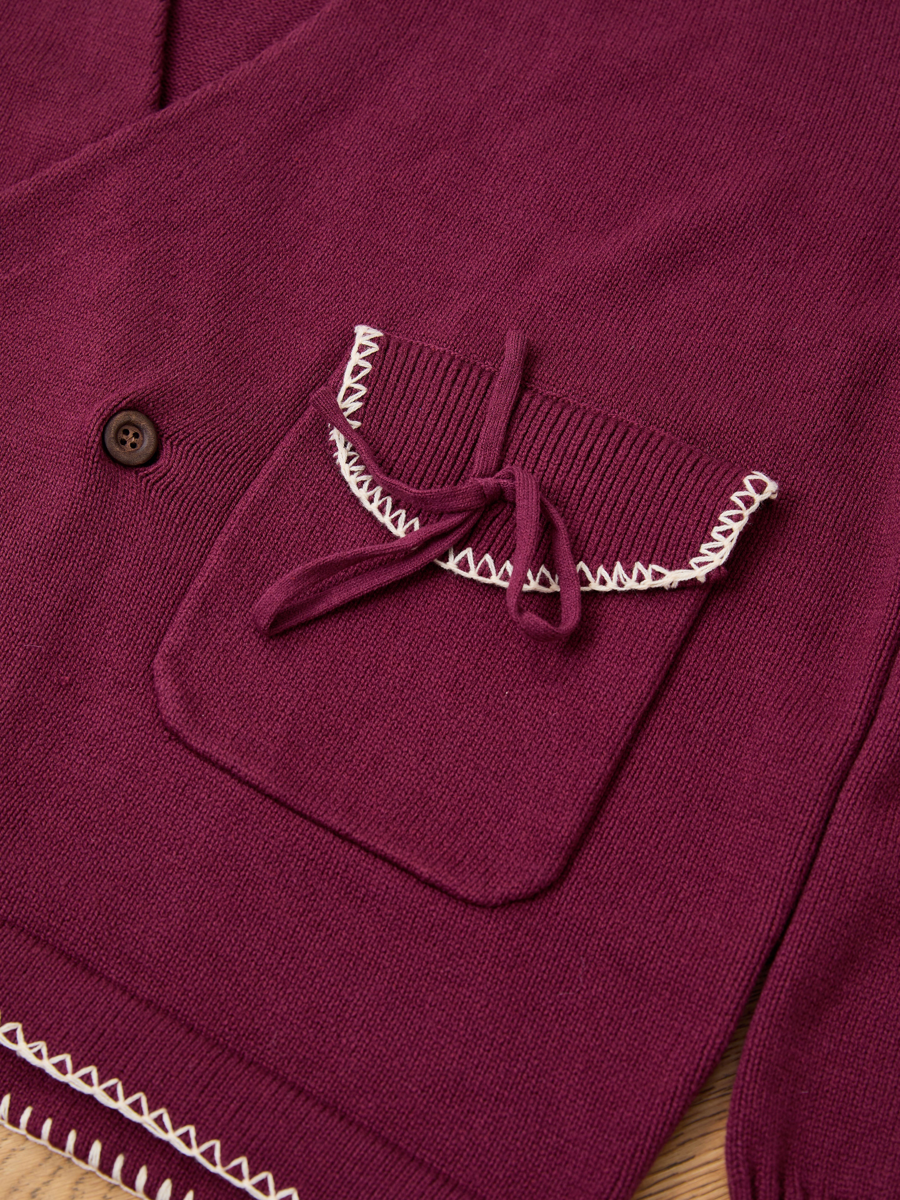 Close-up of FOUND's Double Breasted Bow Cardigan in maroon cotton blend, featuring a front pocket with decorative bow, white stitching accents, and a unisex relaxed fit for versatile comfort.