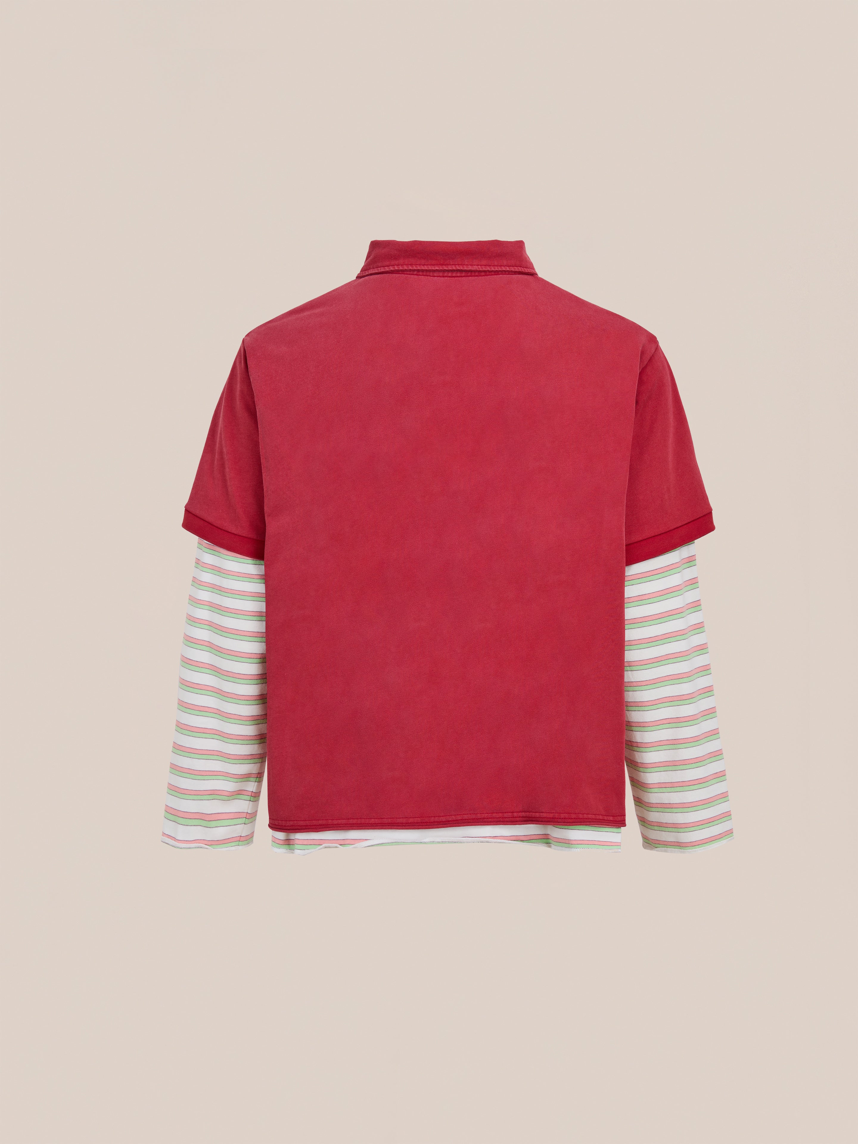 The FOUND Double Layer Stripe Polo features a vintage-inspired, unisex relaxed fit with a red short-sleeve layer over a long-sleeve white shirt with multicolored stripes, shown from the back against a beige background.