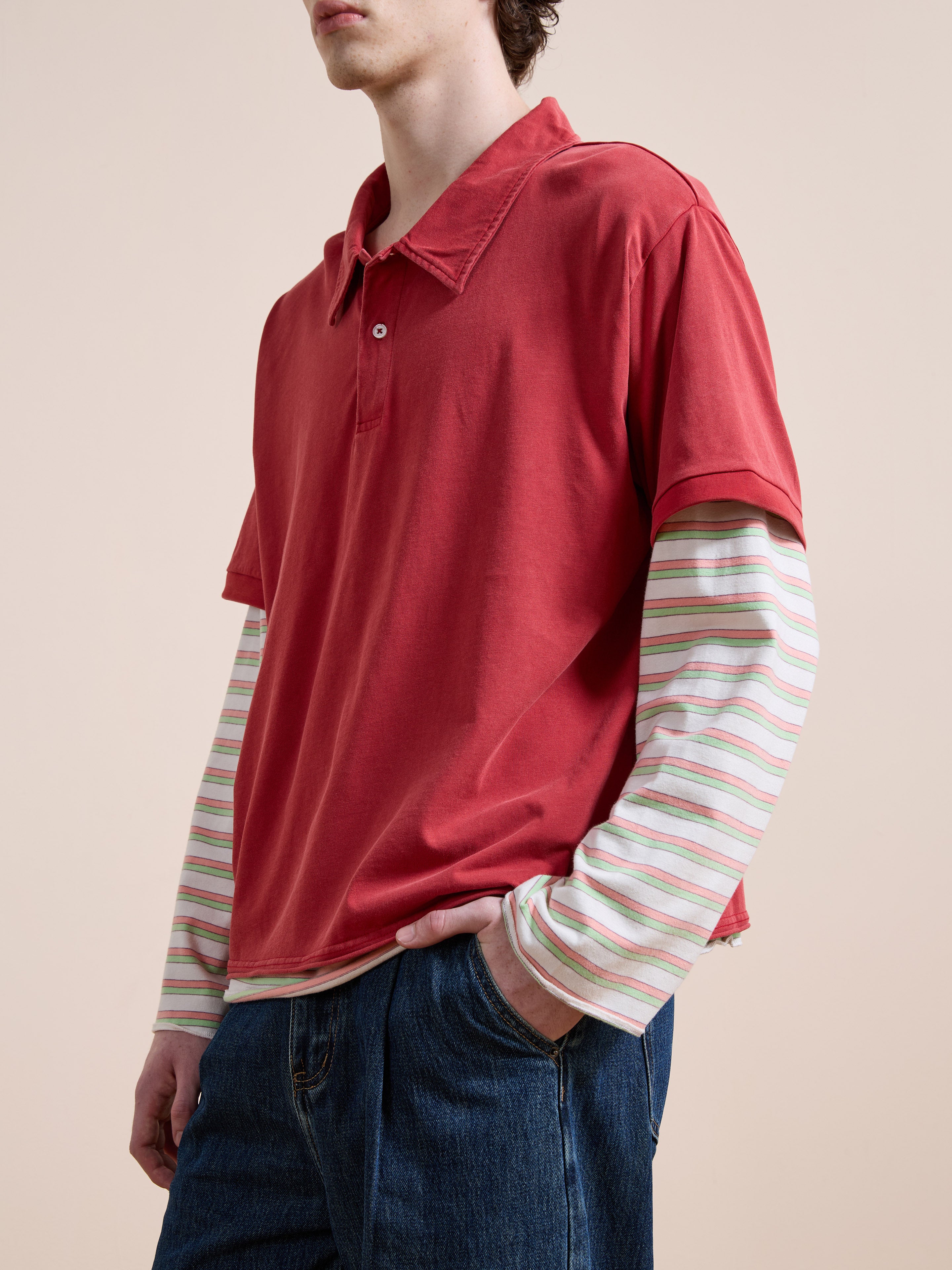 Wearing the FOUND Double Layer Stripe Polo in a unisex relaxed fit over blue jeans, someone stands with one hand in their pocket before a plain backdrop, channeling vintage athletic sportswear style.