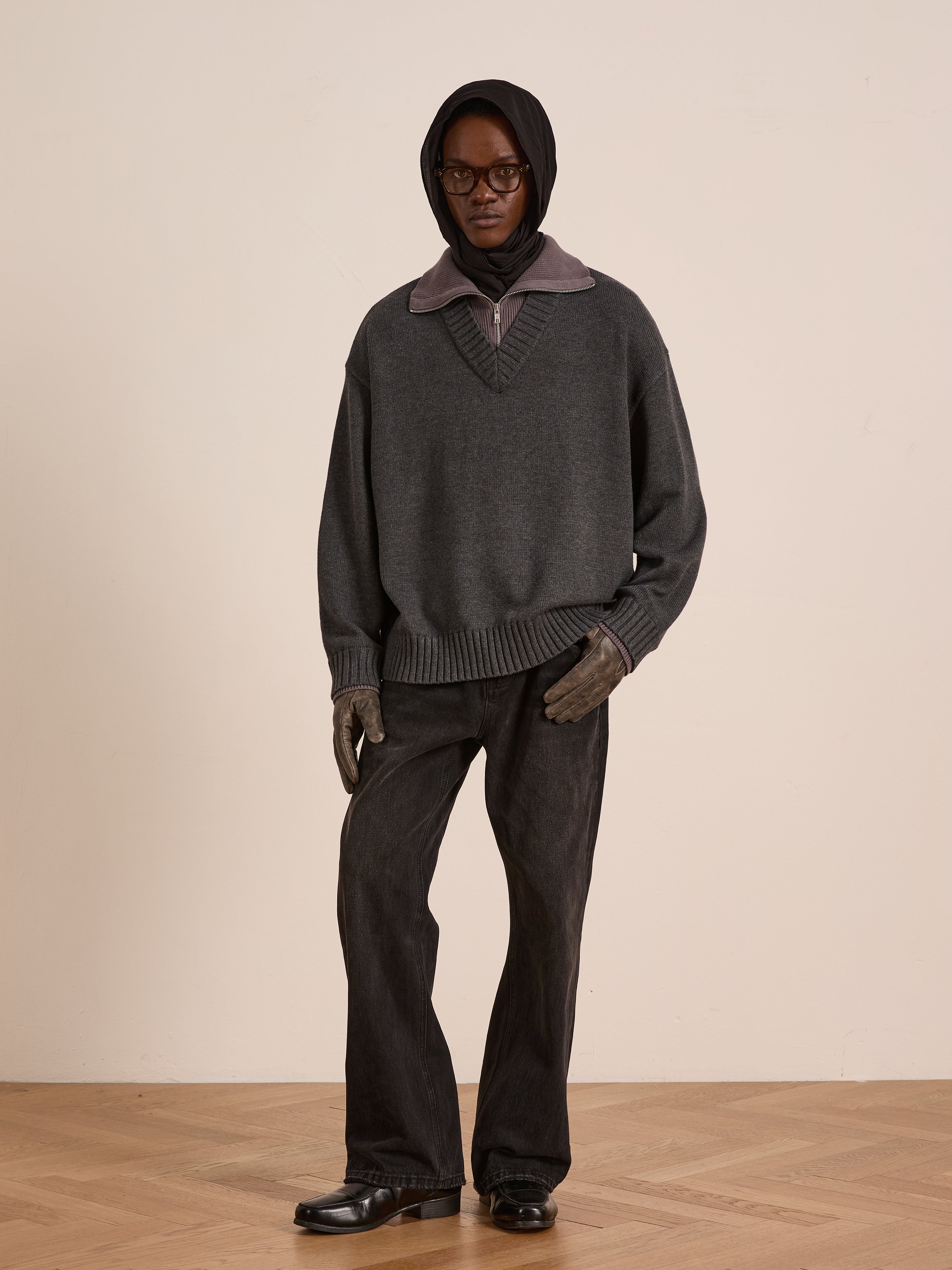 A person wearing a dark hood, glasses, FOUND's Double Layer Sweater over a high-collar shirt, dark gloves, wide-leg black jeans, and black shoes stands against a plain background—ideal for cold-weather layering.