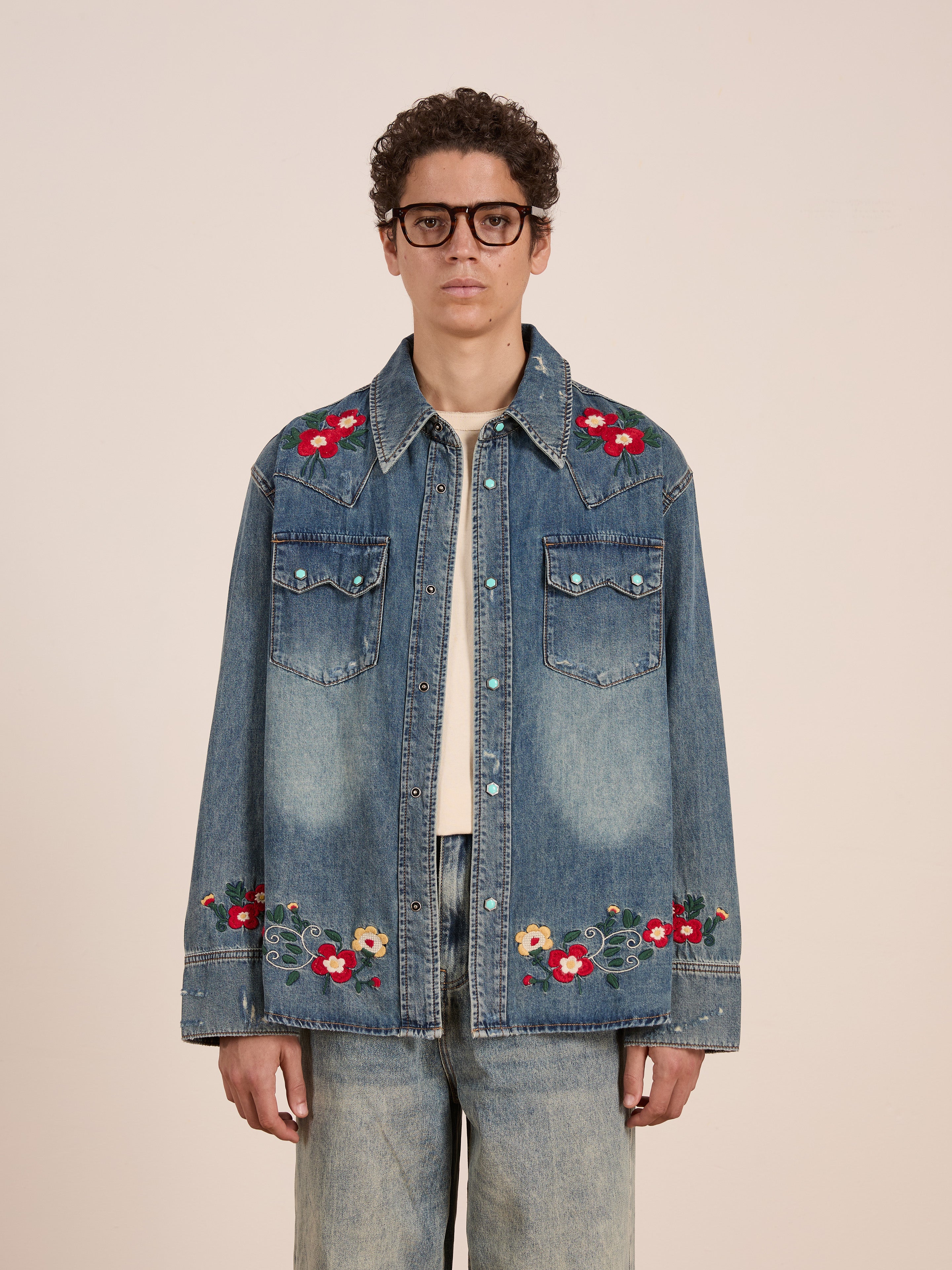 A person wearing glasses and the FOUND Floral Embroidered Western Denim Shirt with light blue jeans stands facing the camera against a plain background.