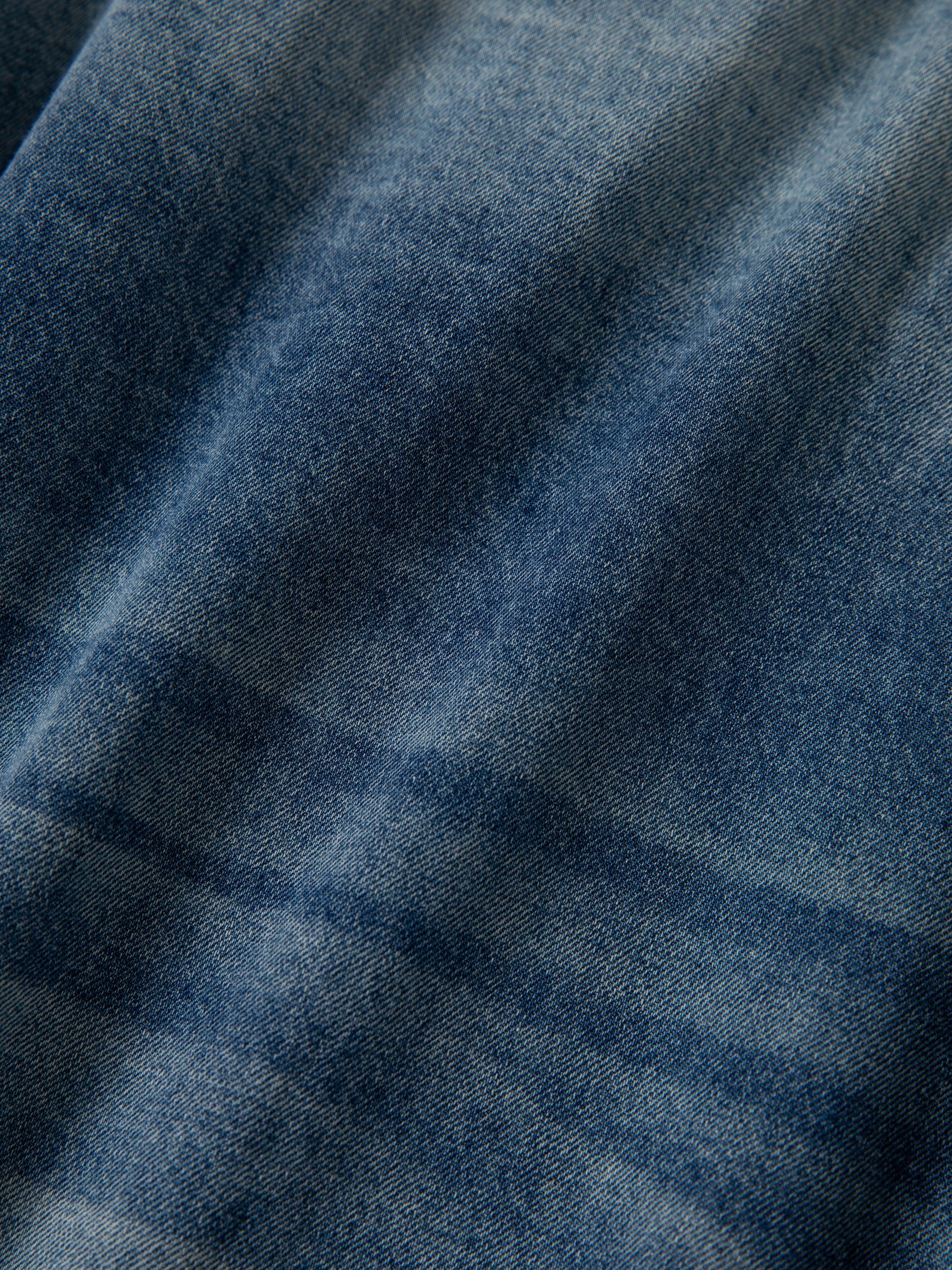 Close-up of FOUND’s Floral Embroidered Western Denim Shirt, showcasing its structured denim texture and subtle color variations.