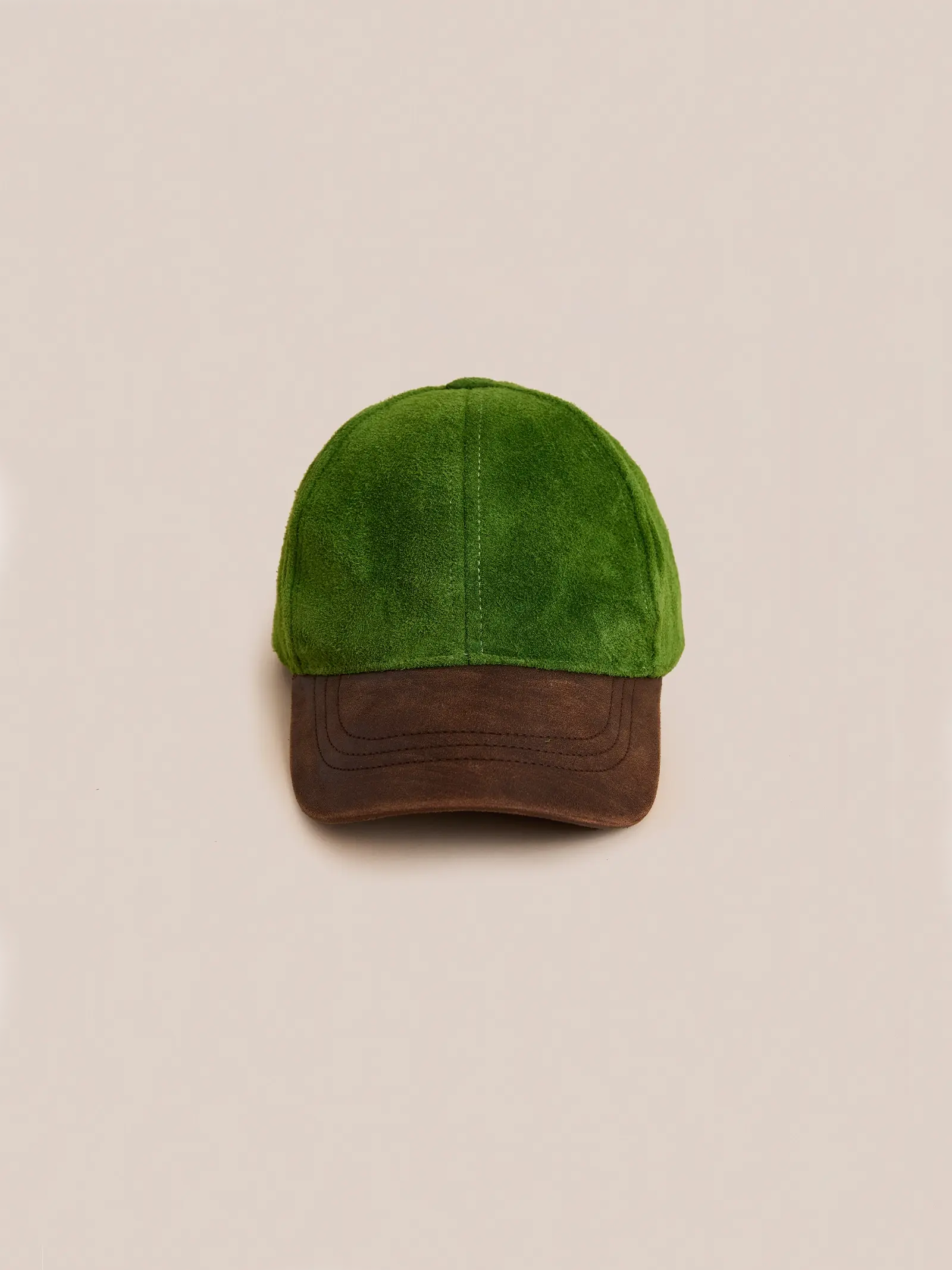 The Found Suede Leather Contrast Distressed Cap features green suede and a distressed brown leather brim, displayed against a plain beige background.