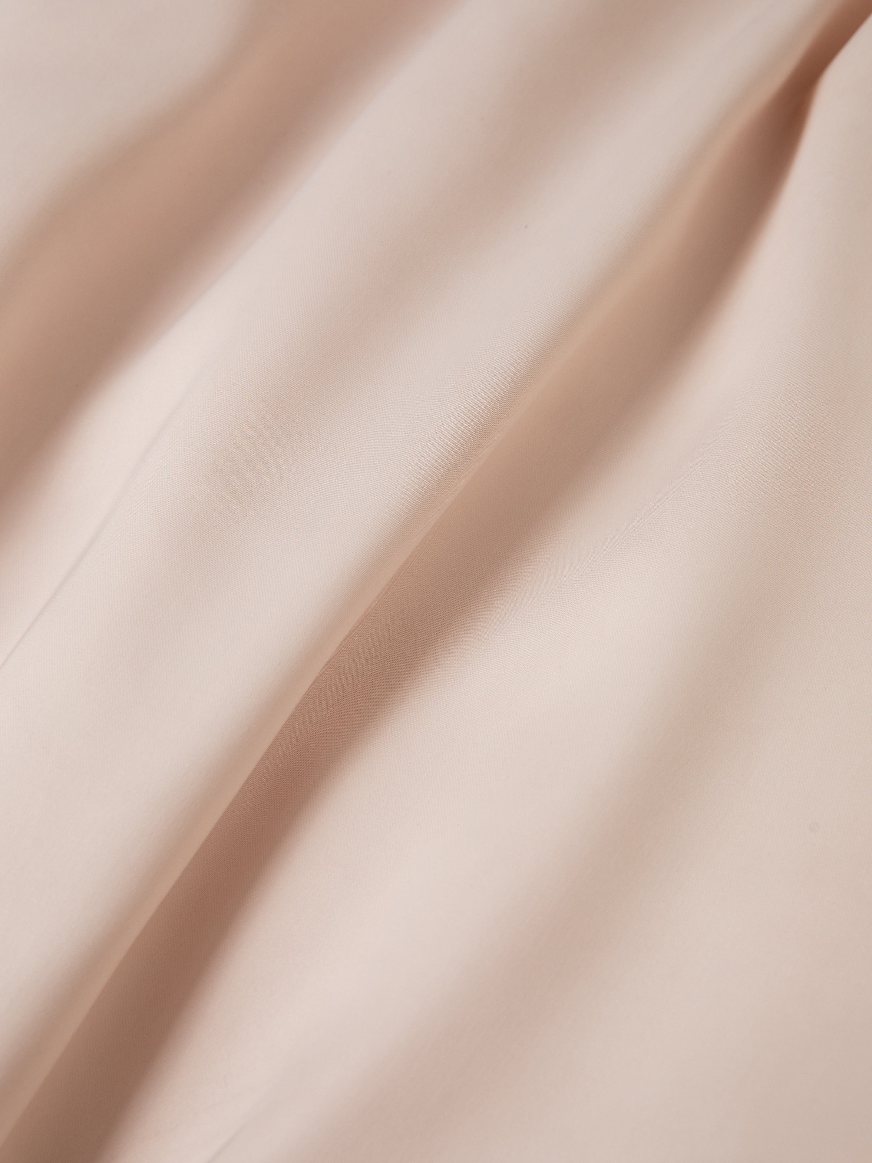 Close-up view of the Daman Satin Jacket by FOUND, showcasing its soft beige fabric with gentle folds and a smooth texture.