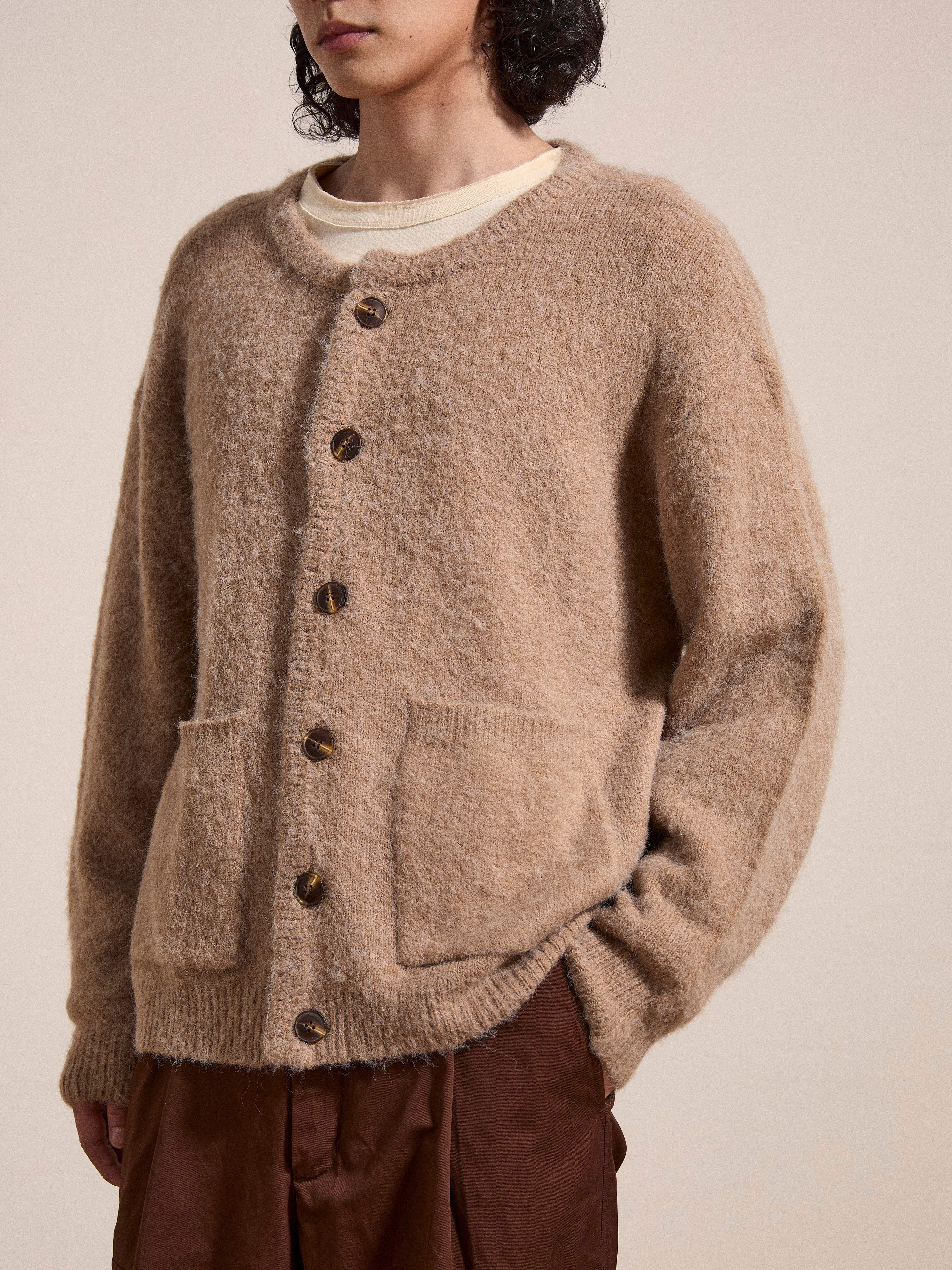 Person wearing an oversized, beige FOUND Mohair Cardigan with tortoise buttons and two front pockets over a white t-shirt.