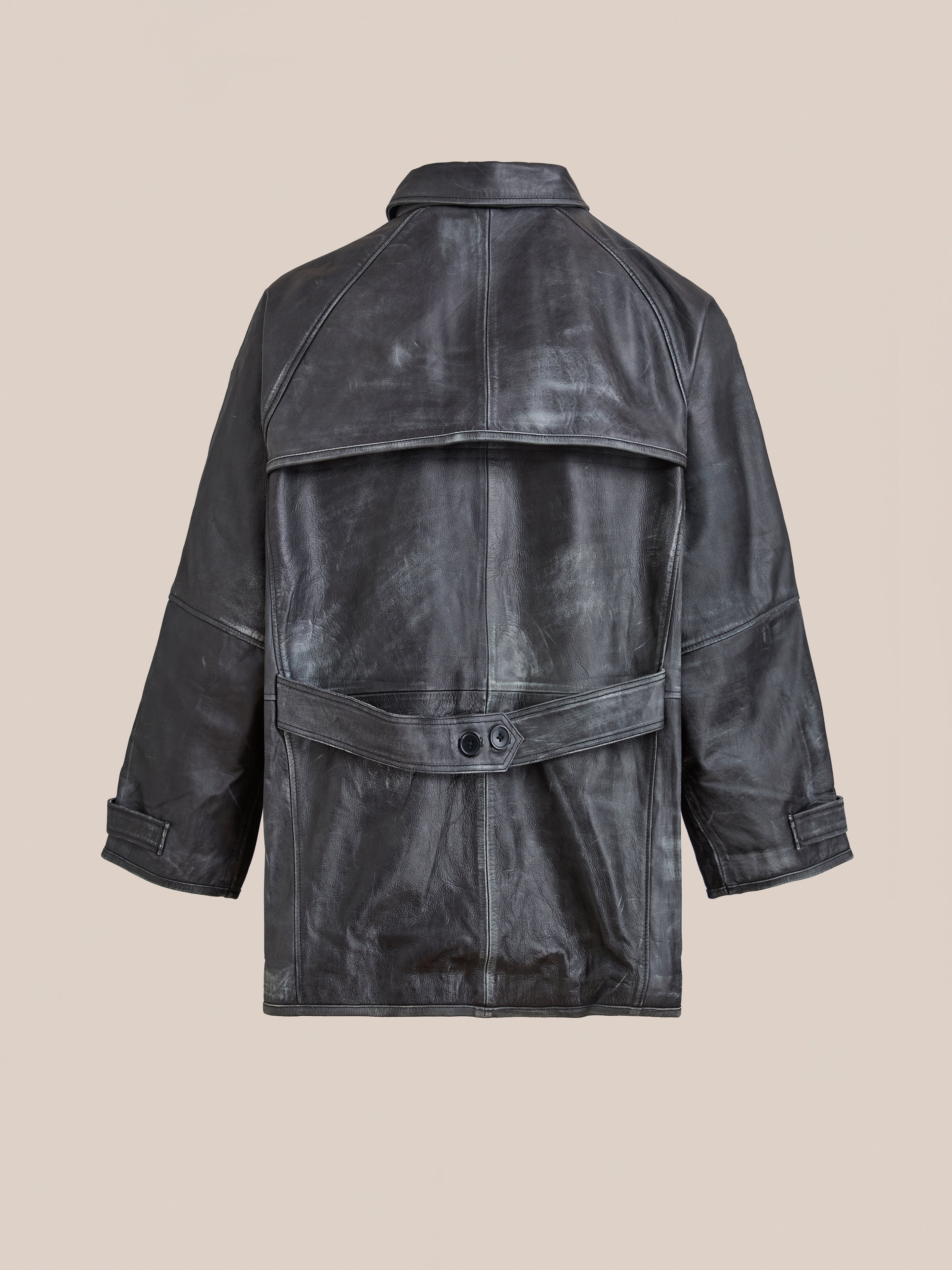 The FOUND Distressed Leather Fireman Clasp Jacket is a unisex black leather jacket with a wide collar and belt detail, shown from the back against a beige background.