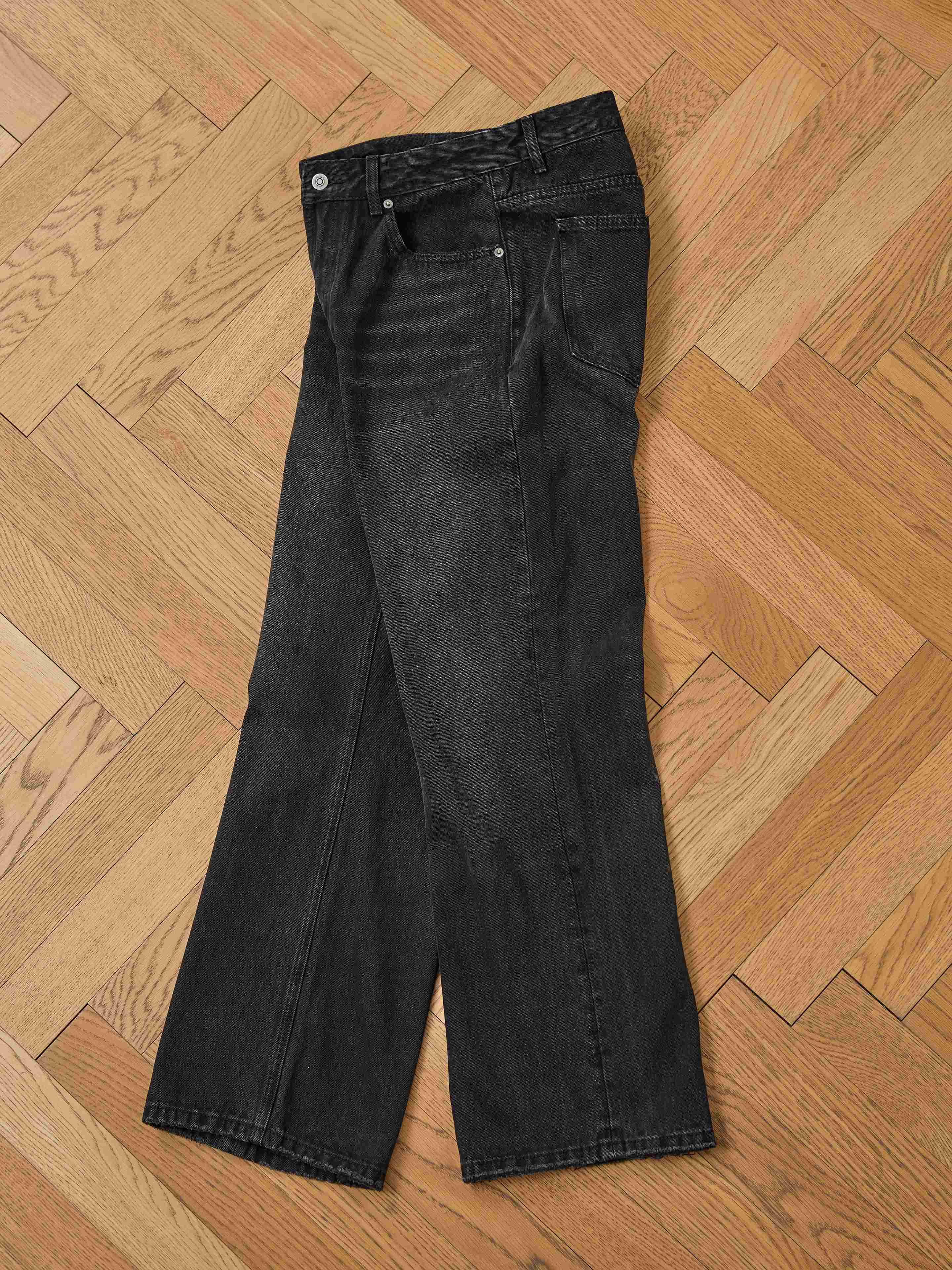 A pair of Found Flare Jeans lies flat on a wooden herringbone-patterned floor.