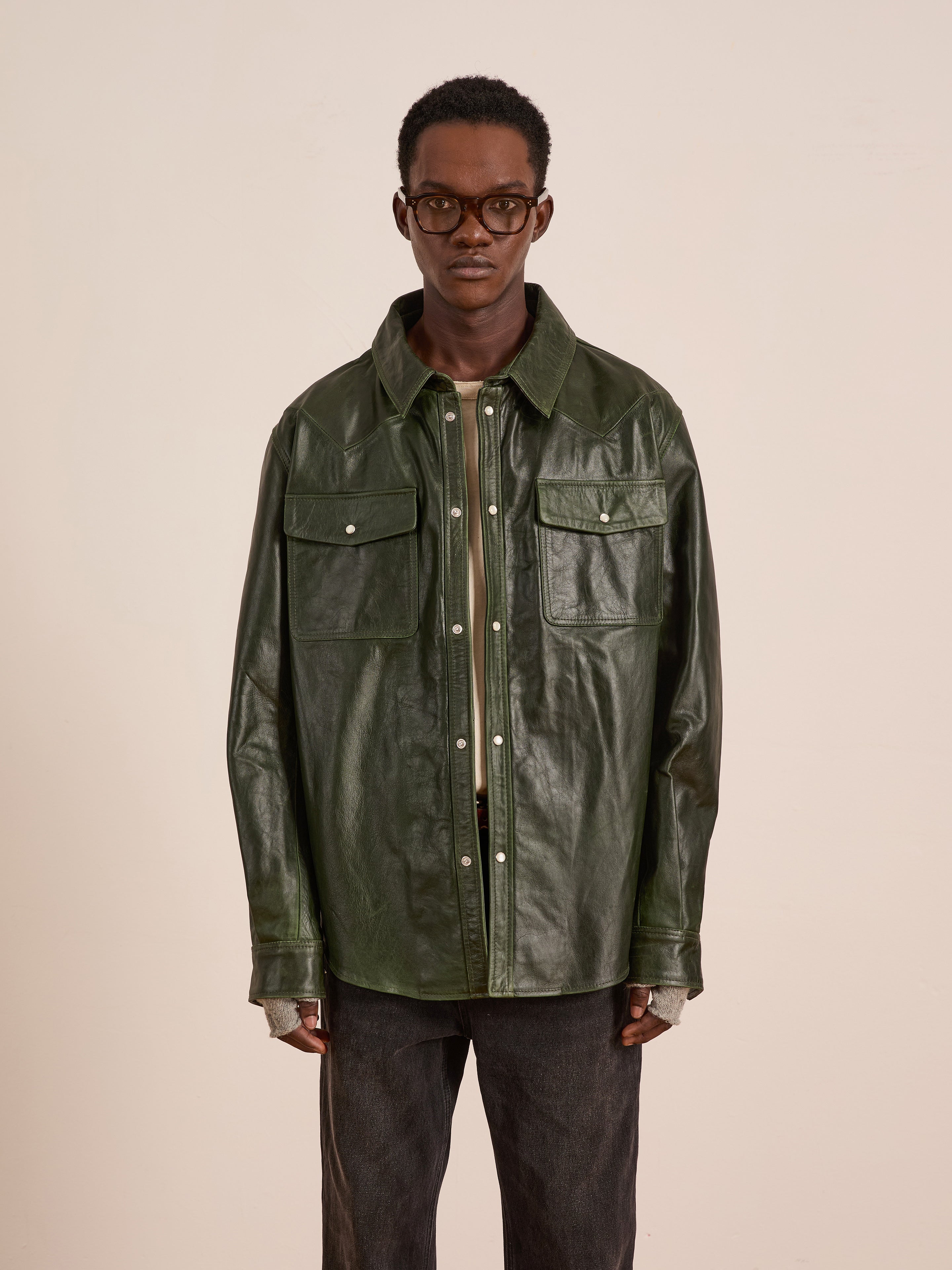 A person wearing glasses, the FOUND Forest Leather Western Shirt with front pockets, and dark pants stands against a plain light background.