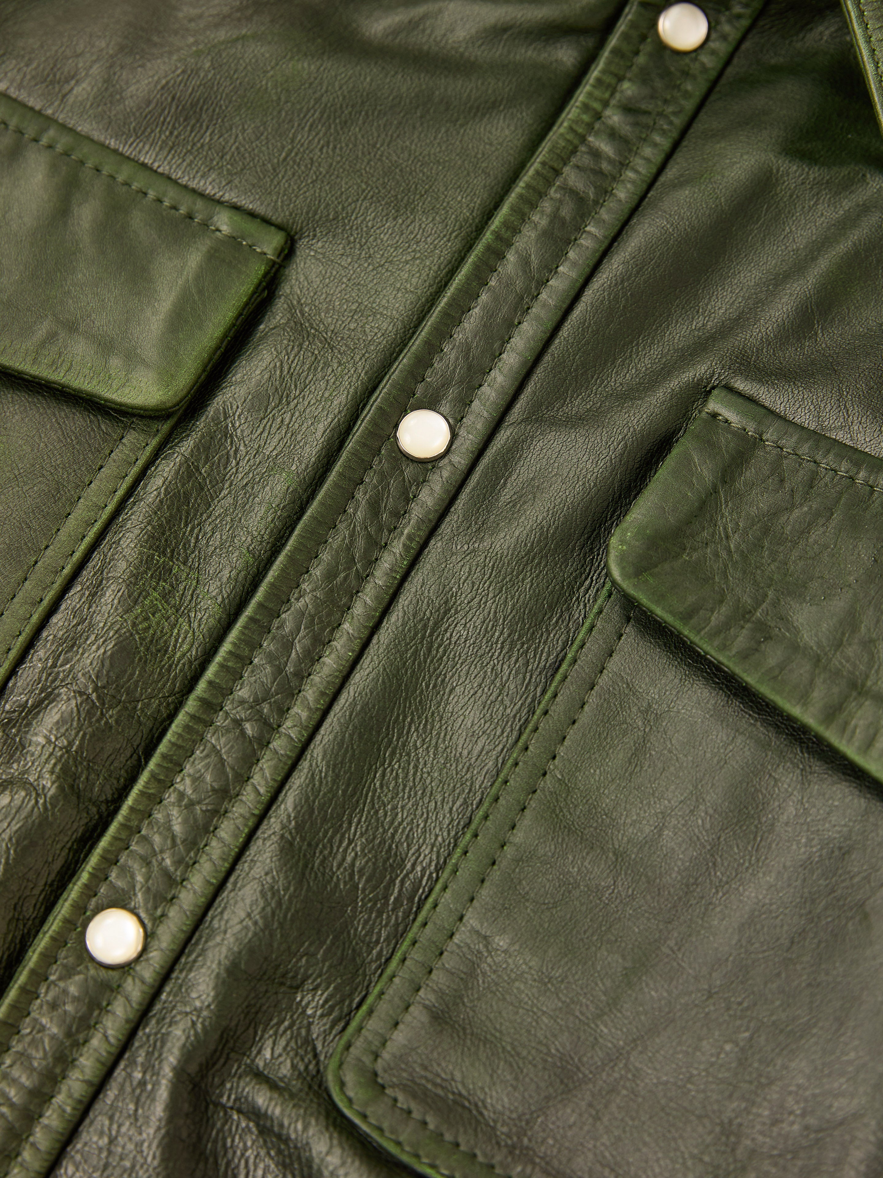 Close-up of the FOUND Forest Leather Western Shirt in dark green leather, with visible stitching, two front pockets, and silver snap buttons.