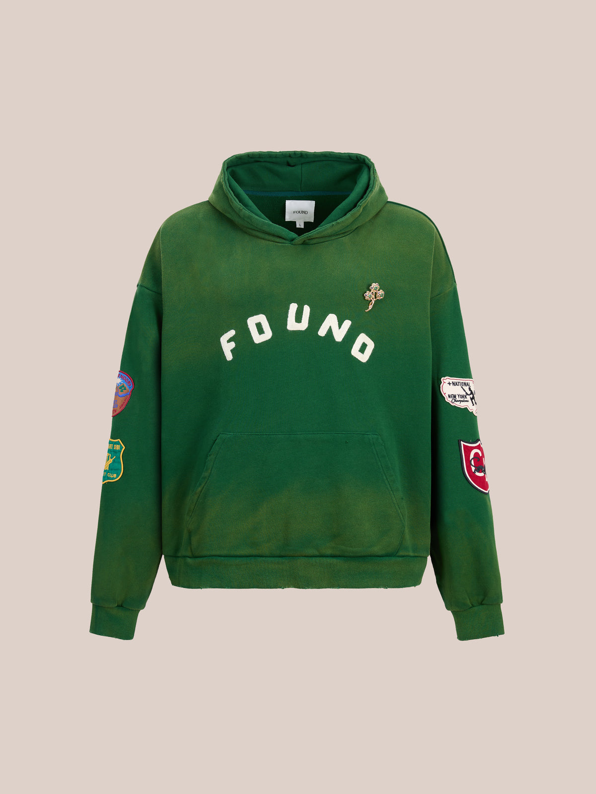 The Found Logo Patch Hoodie by FOUND features a forest green color, “FOUND” on the chest, sleeve patches, a left pin, and a unisex relaxed fit.