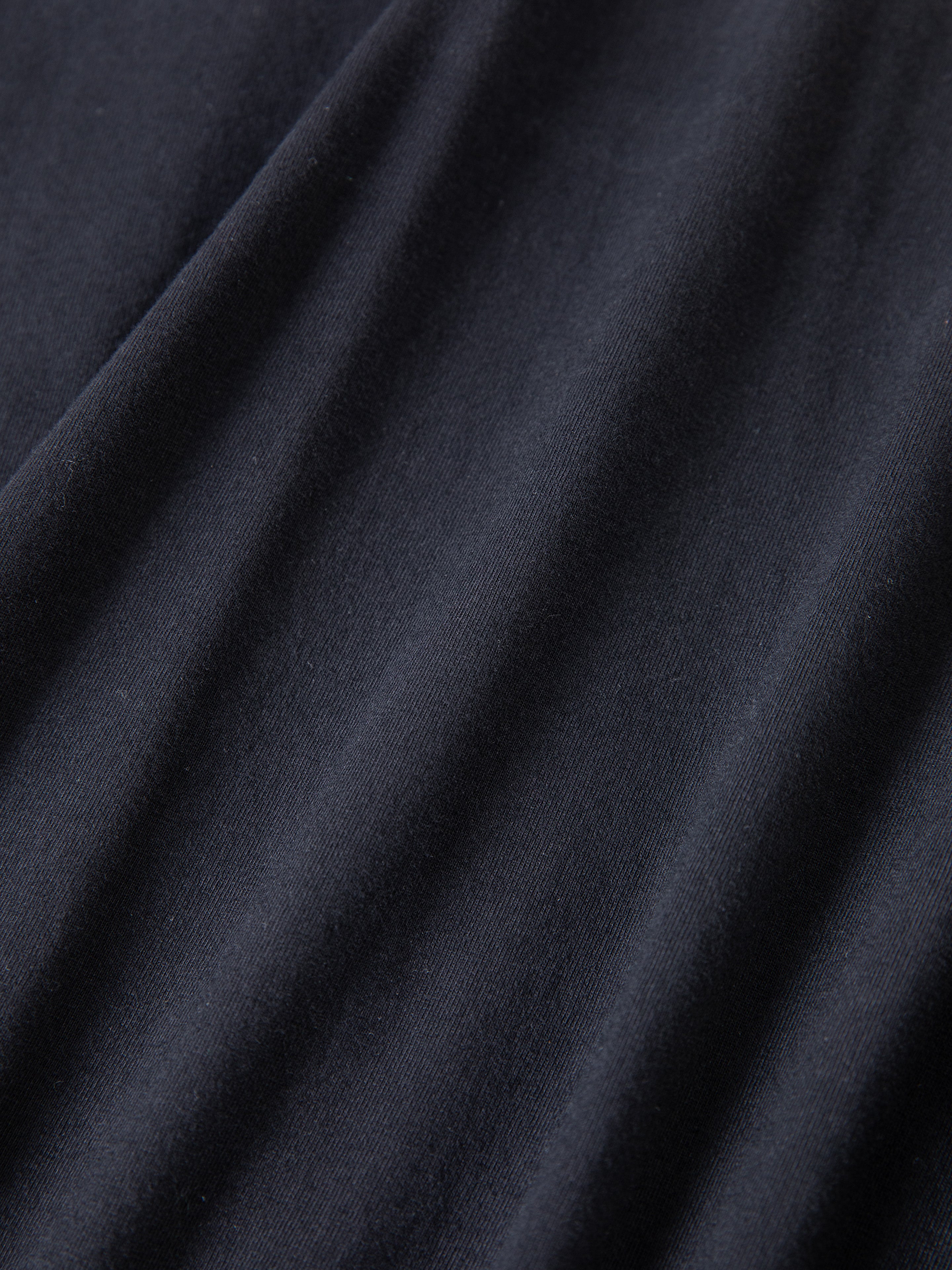 Close-up of soft black fabric with visible folds, featuring embroidered floral graphics inspired by the FOUND Garden Bloom Embroidered LS Tee.