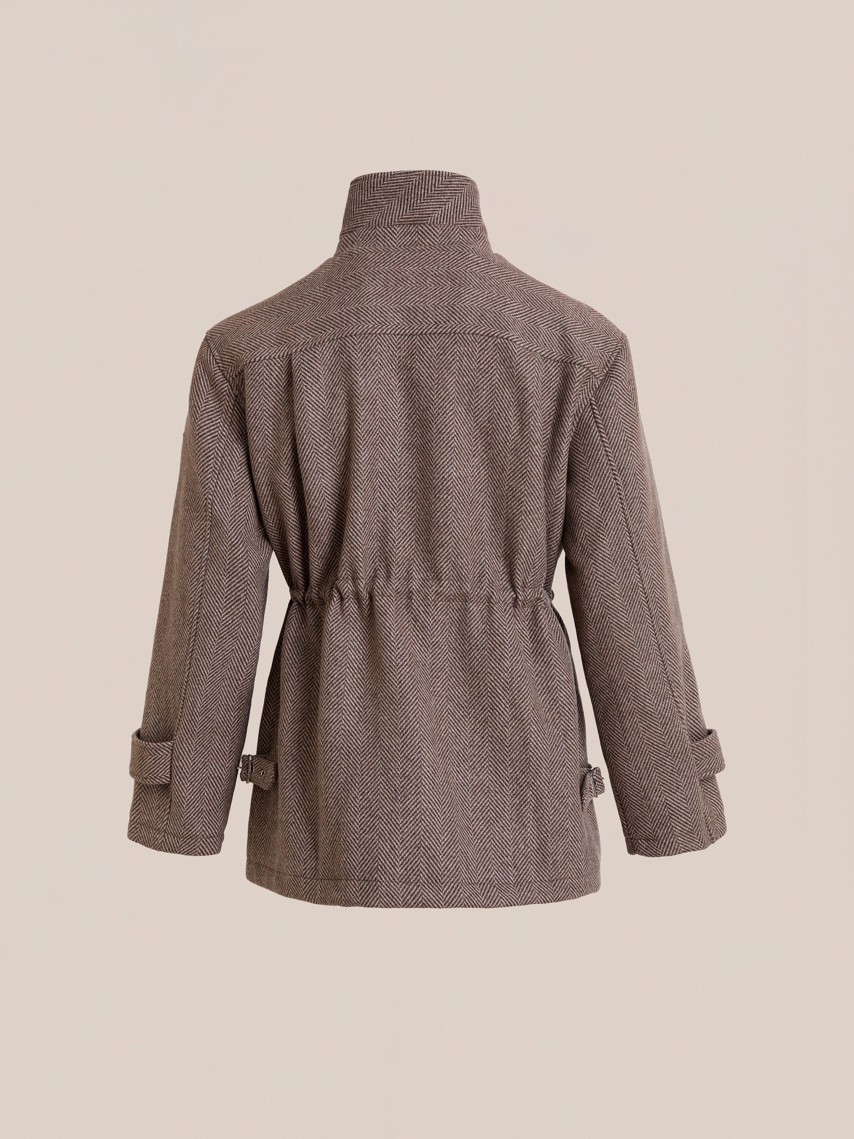 Back view of the FOUND Herringbone Wool Barn Jacket in brown herringbone wool blend, with long sleeves, high collar, unisex relaxed fit, adjustable waist, and cuff straps, shown against a plain beige background.