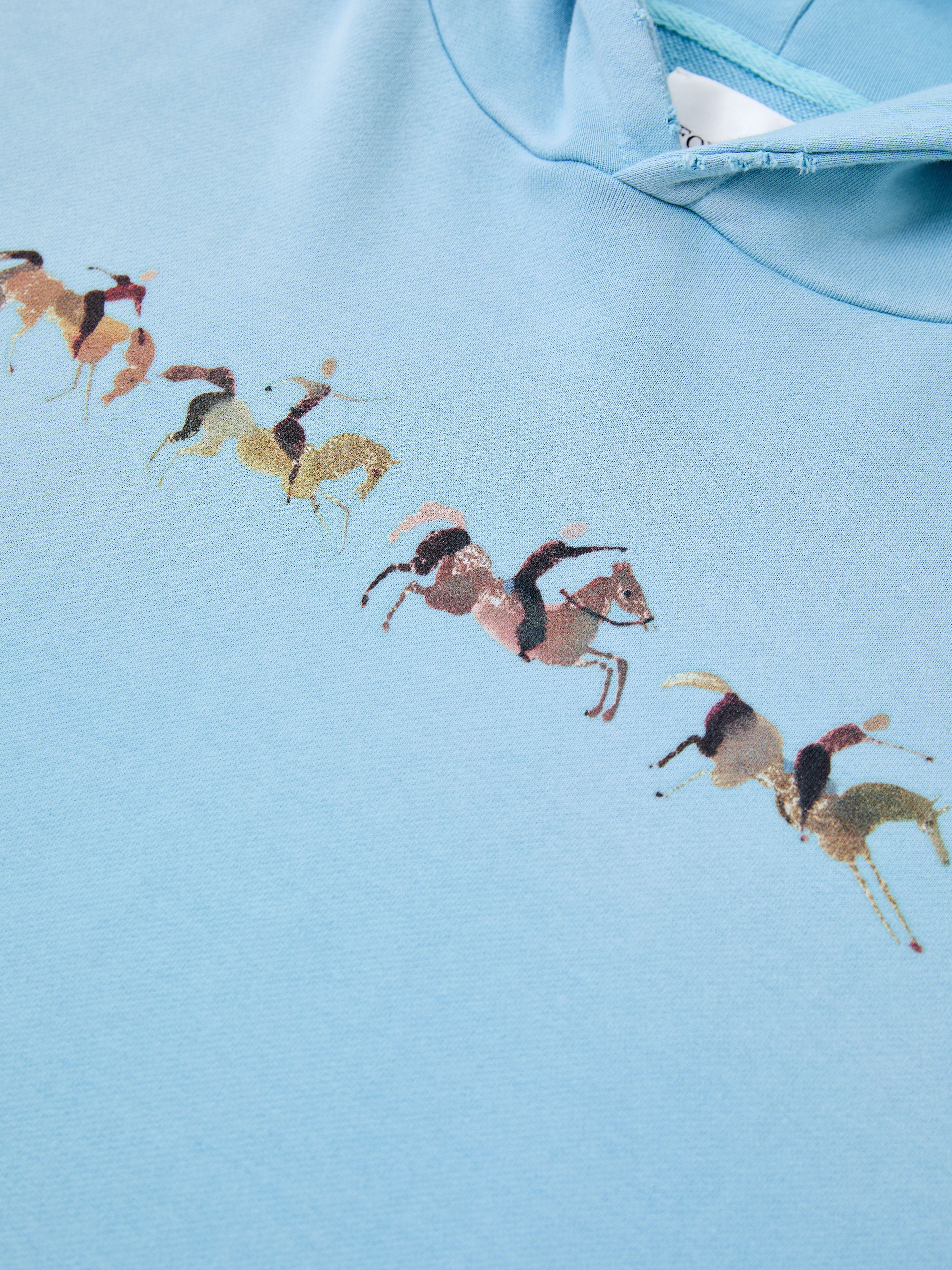 FOUND's Horse Line Hoodie features light blue French Terry cotton with a diagonal print of multicolored polo players on horseback—ideal for those seeking a vintage-inspired look.