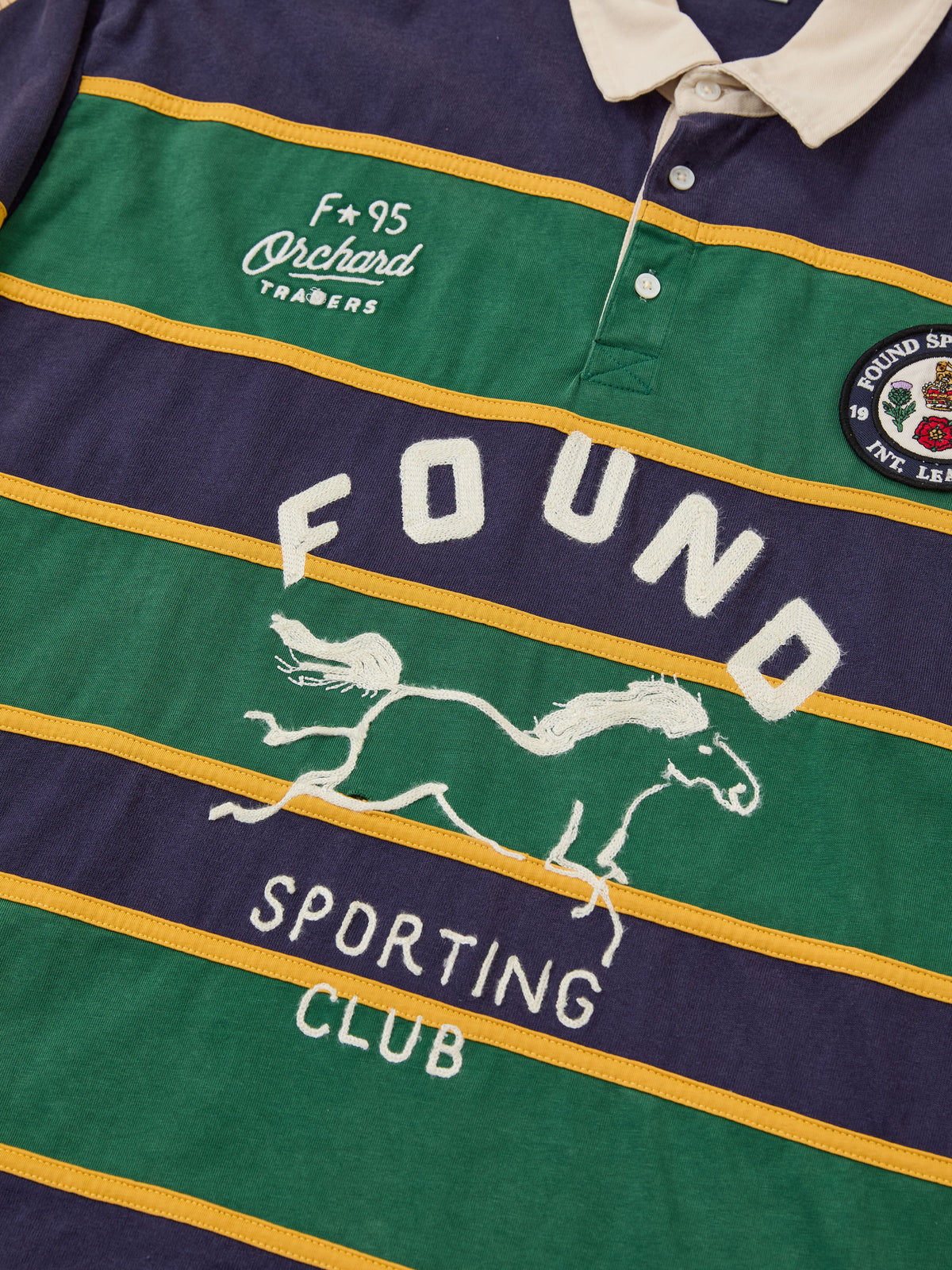 FOUND Horse Logo Rugby: Unisex shirt with yellow/green stripes, white collar, horse logo, “FOUND SPORTING CLUB” text, and vintage team-style chest badges.