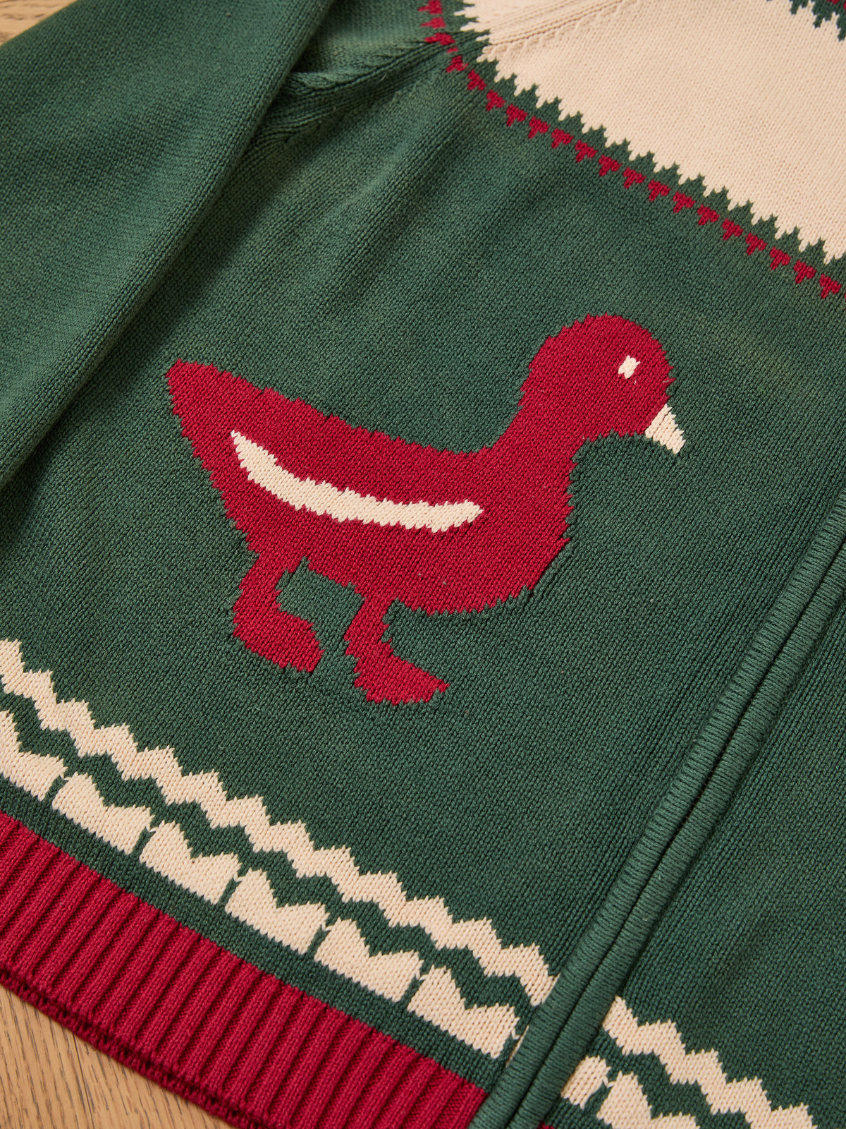 The Isles Sweater by FOUND is a green unisex knit featuring red and white duck motifs and white geometric patterns on the hem and edges for a vintage vibe.