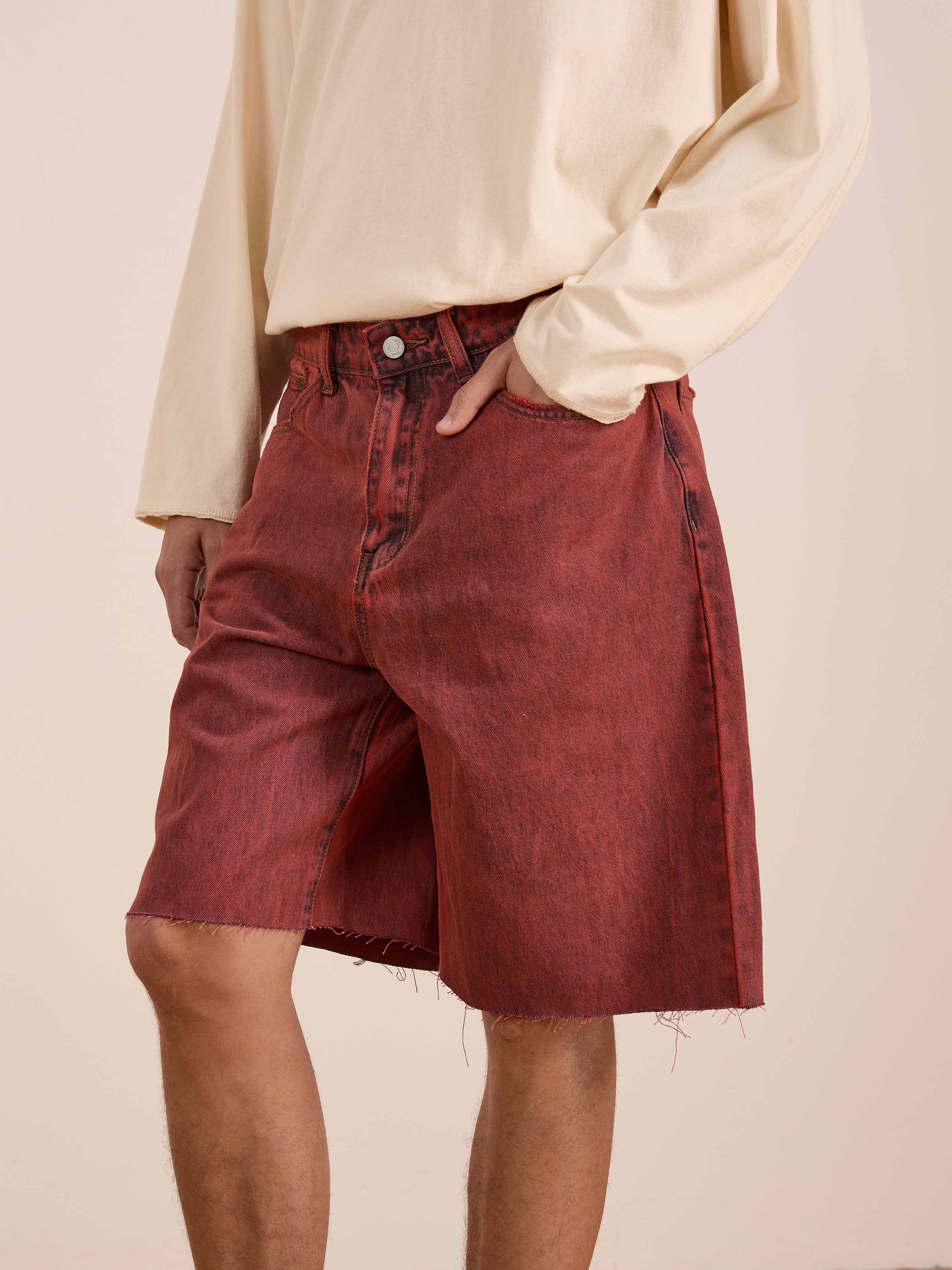 A person wearing a cream long-sleeve shirt and FOUND Lacy Jean Jorts in vintage red wash stands against a plain background.