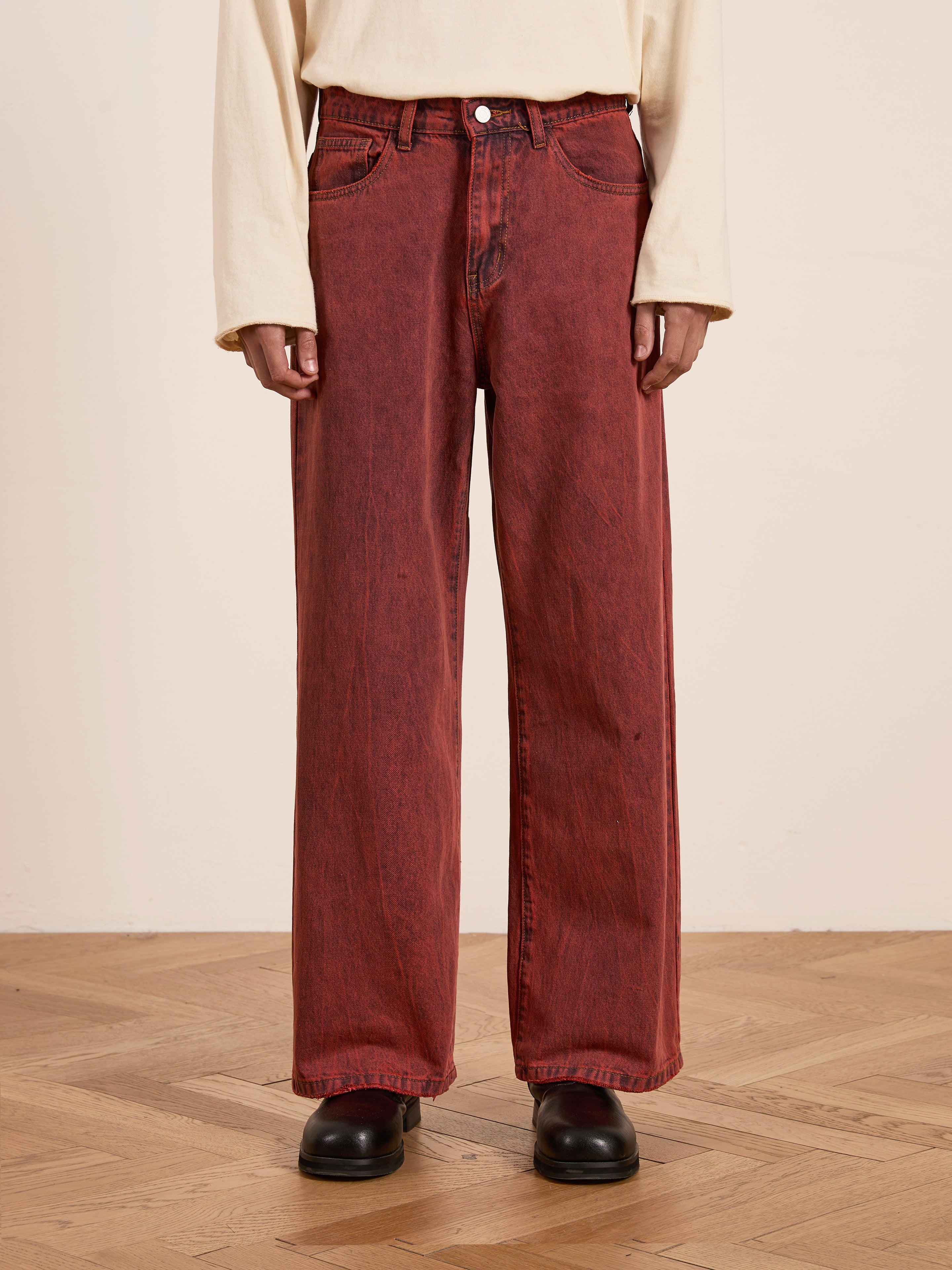 A person in FOUND's Lacy Baggy Jeans with a high-waisted, wide-leg vintage red wash and a cream sweater stands gracefully on a wooden floor.