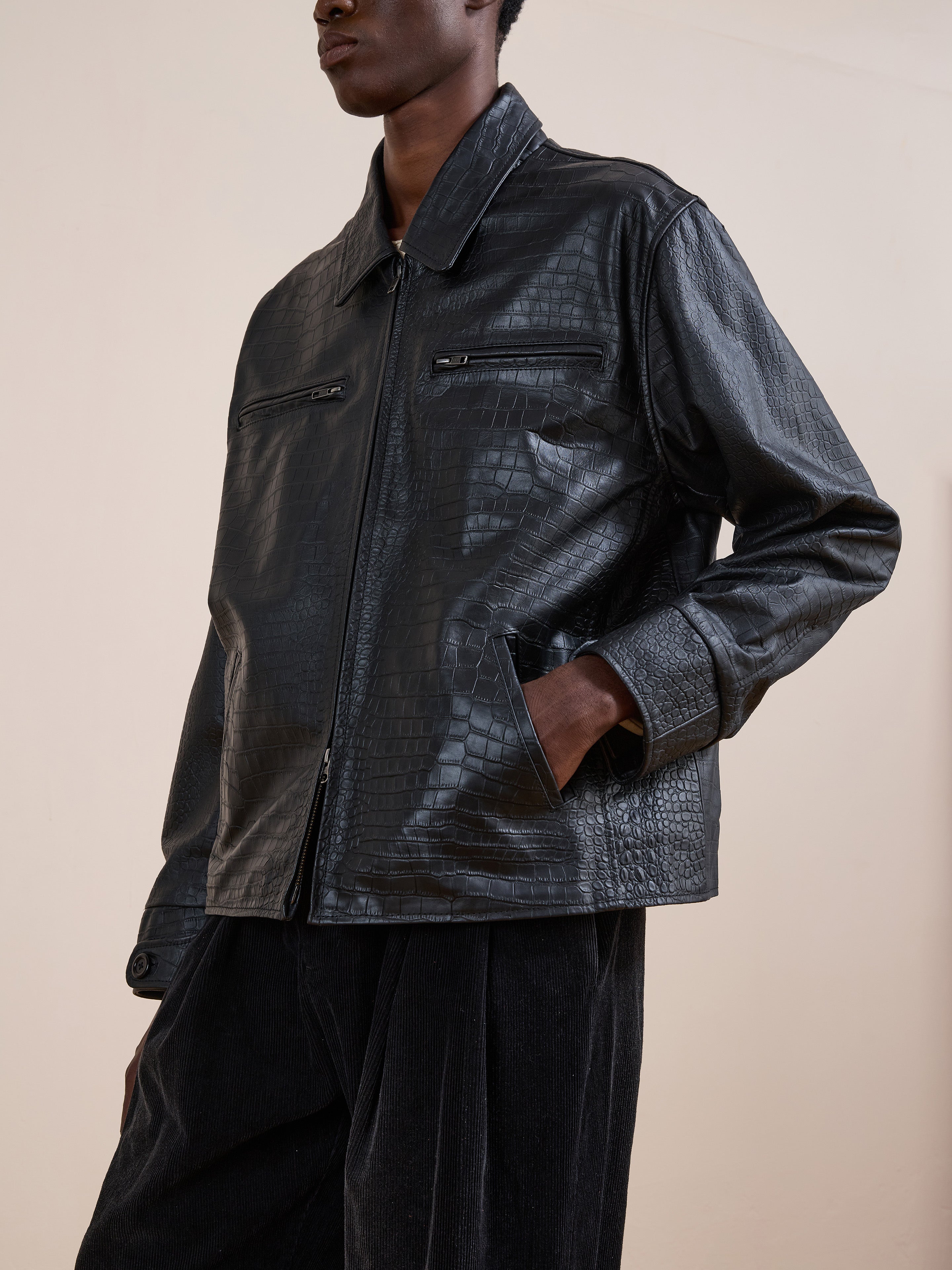 A person models the FOUND Marlboro Croc Embossed Leather Racer Jacket, featuring a black crocodile-textured leather, front zipper, zippered chest pockets, and a unisex relaxed fit with a subtle racing silhouette against a plain background.