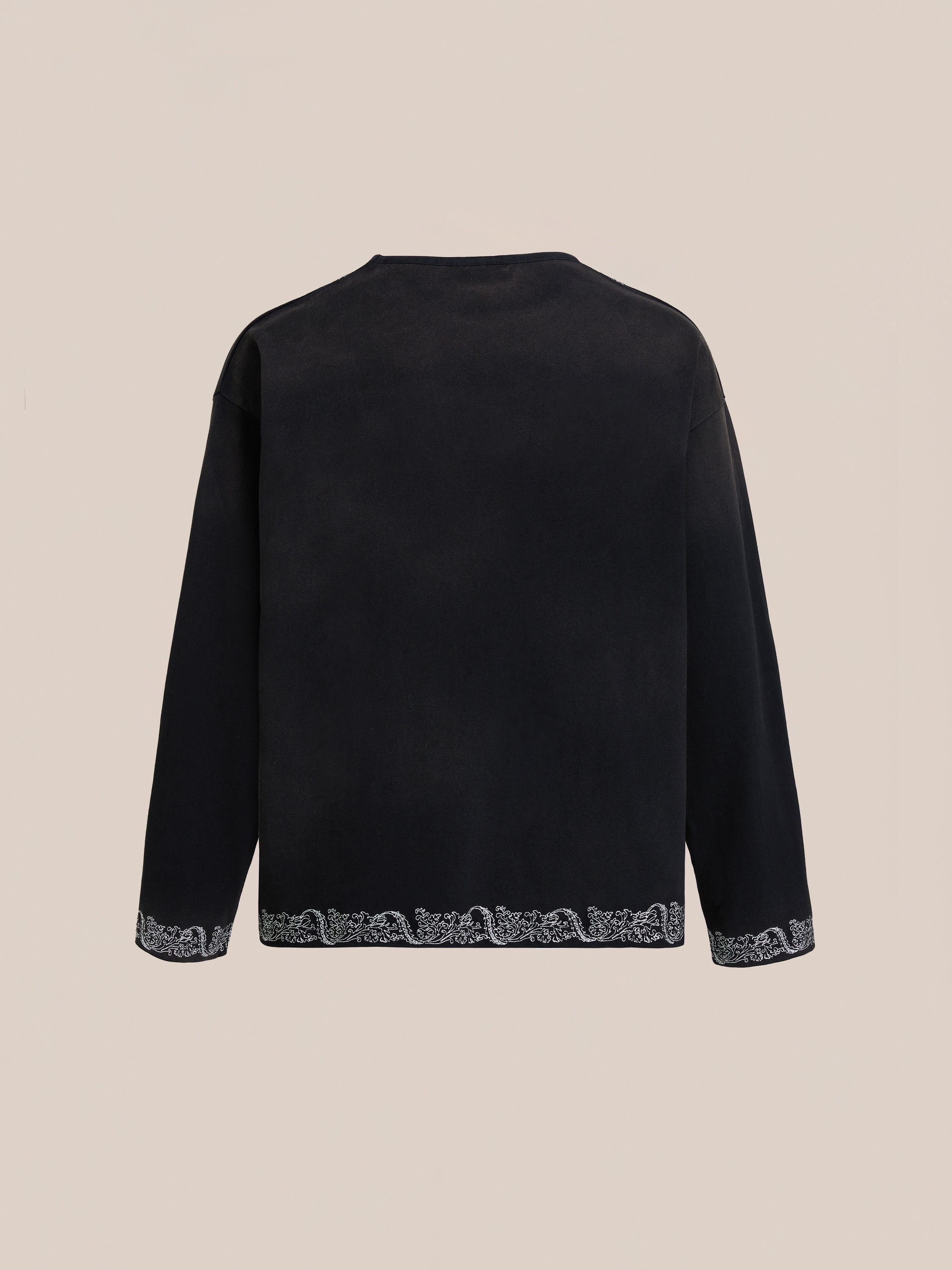 The FOUND Metallic Long Sleeve Embroidered Tee is shown from the back with a straight hem and subtle white embroidery on the cuffs and bottom edge, offering a relaxed unisex fit in vintage black.