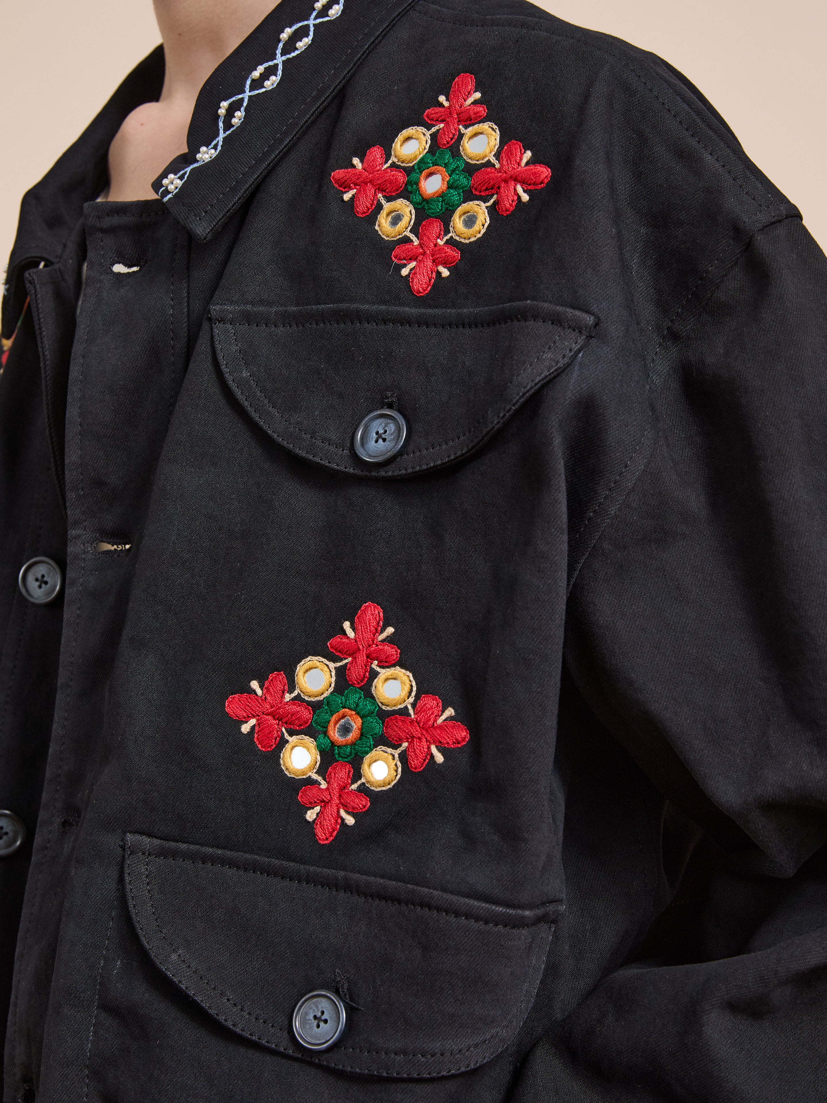 Close-up of the Found Mirror Ornament Hand Embroidered Work Jacket, showcasing vibrant red, green, and yellow floral Aari embroidery and buttoned flap pockets.
