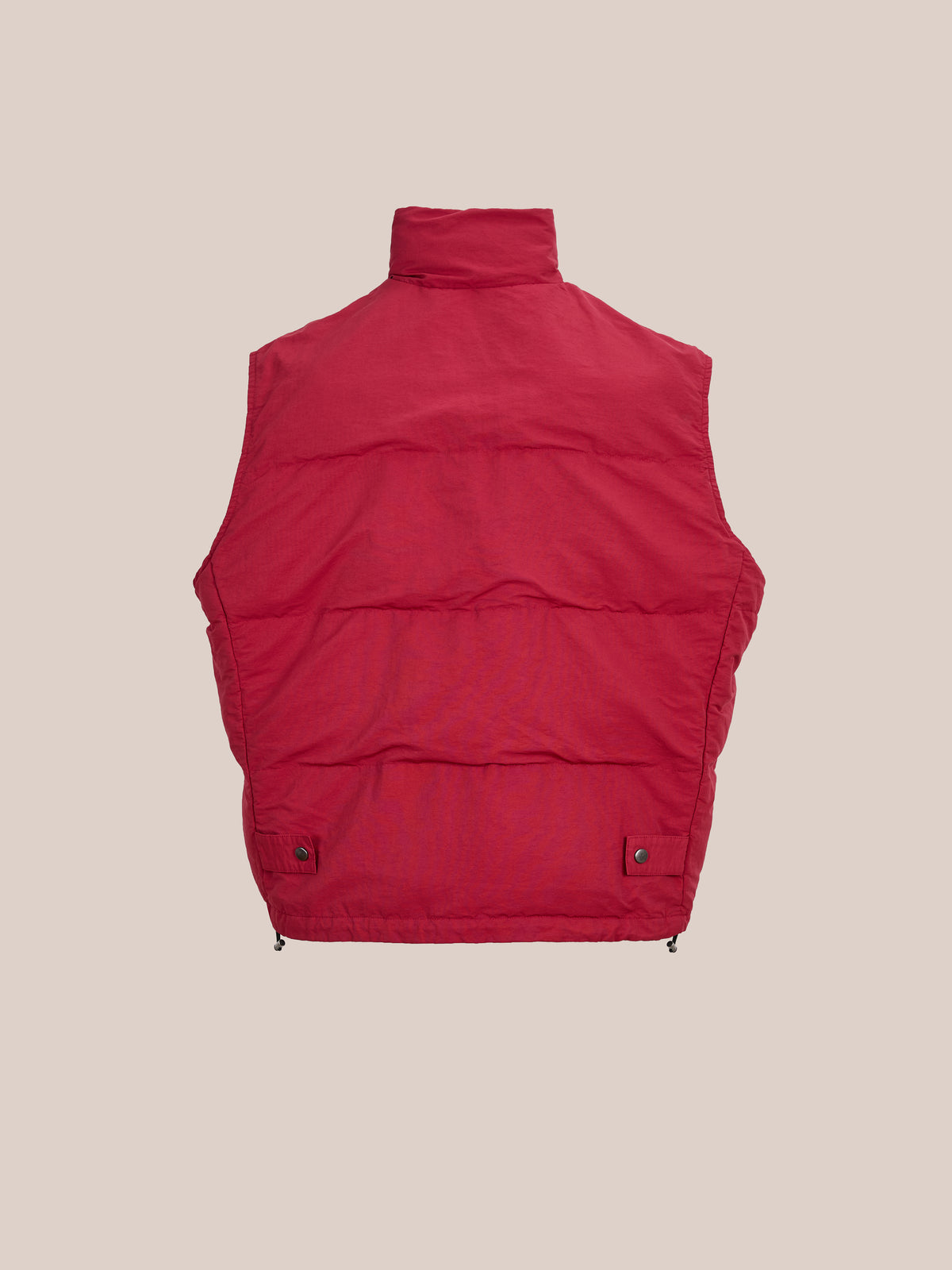 The FOUND Patch Down Vest in red is shown flat on a beige background, highlighting the back view with a high collar and snap details at the hem.