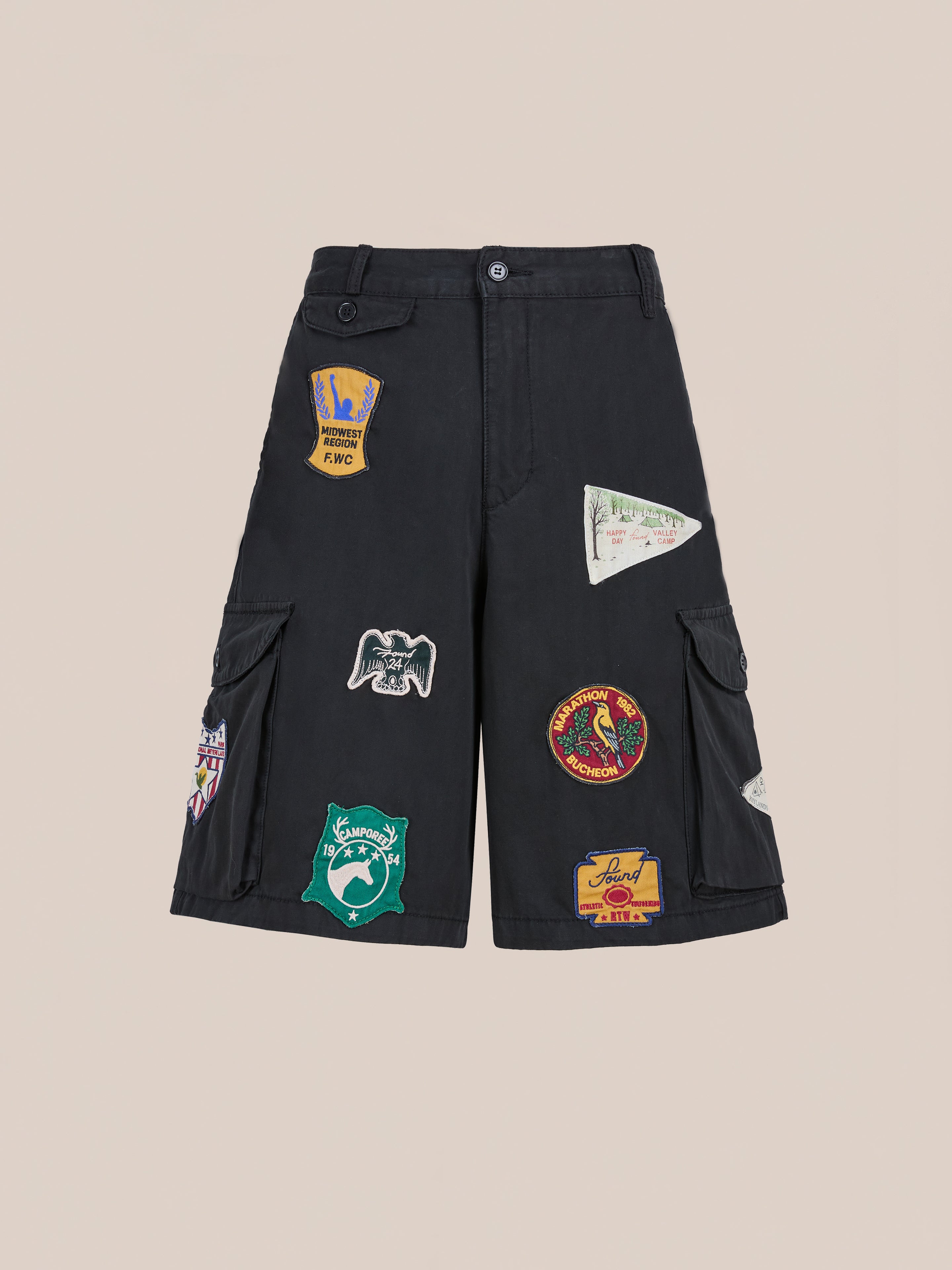 Found Patchwork Cargo Shorts: unisex relaxed fit in vintage black wash with multiple colorful embroidered patches on the front and side pockets, showcased against a plain background.