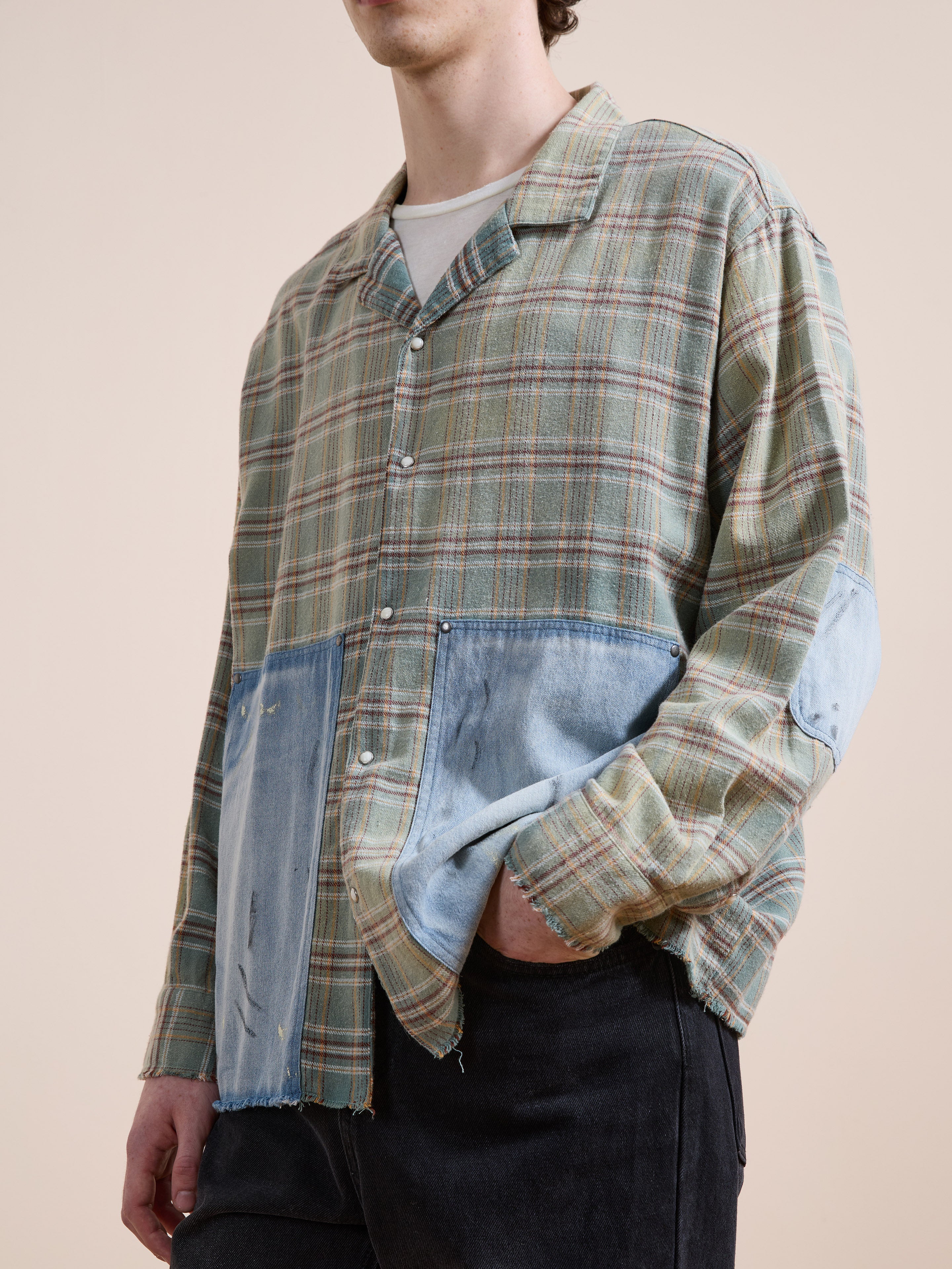 A person wears the FOUND Plaid Denim Shirt, featuring carpenter-style pockets and patchwork accents, styled with black pants and a white tee for a fresh approach to unisex workwear.