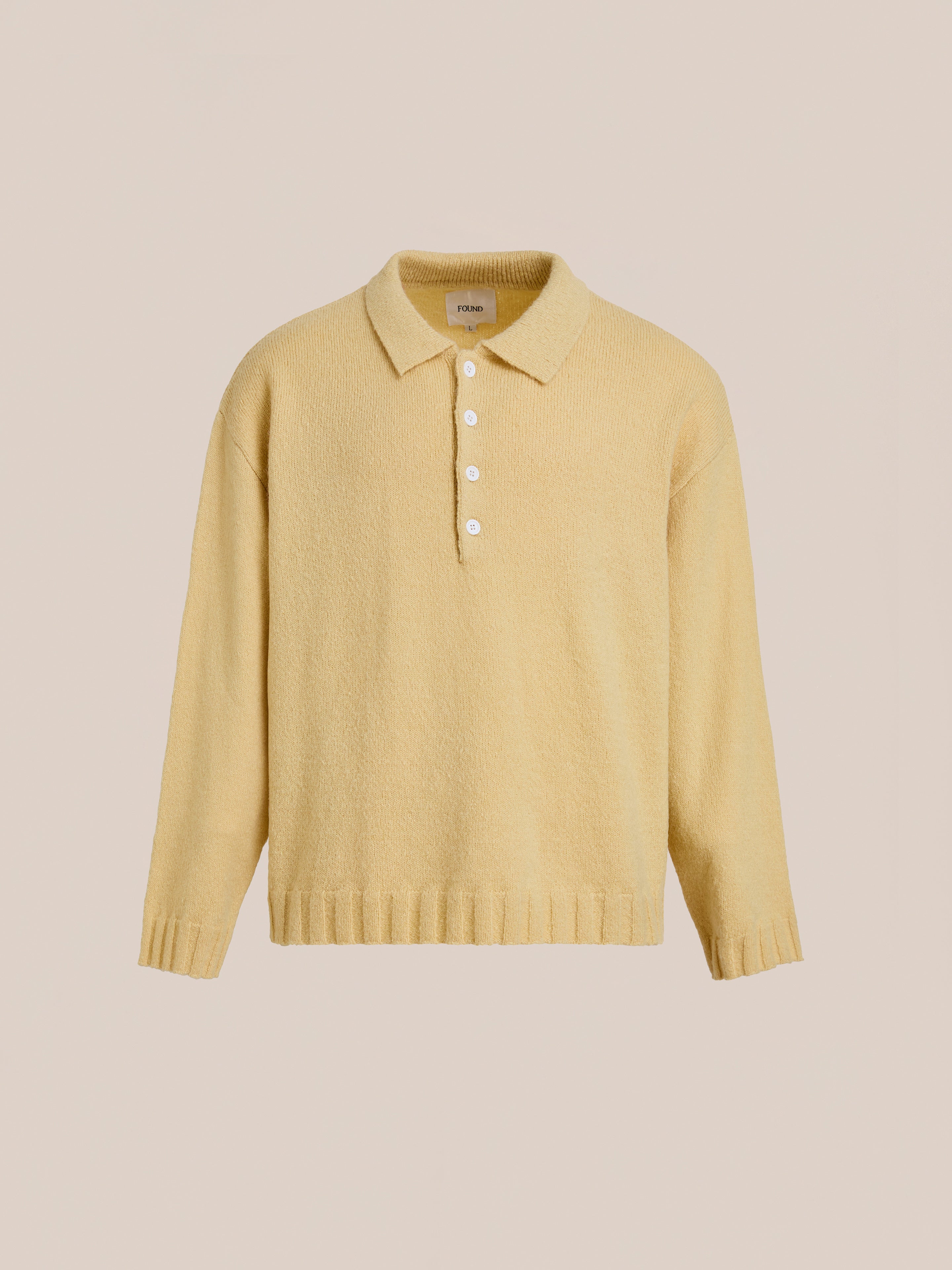 The FOUND Knit LS Polo Sweater features a light yellow hue, collar, five white buttons, and soft brushed knit fabric, shown against a plain beige background.