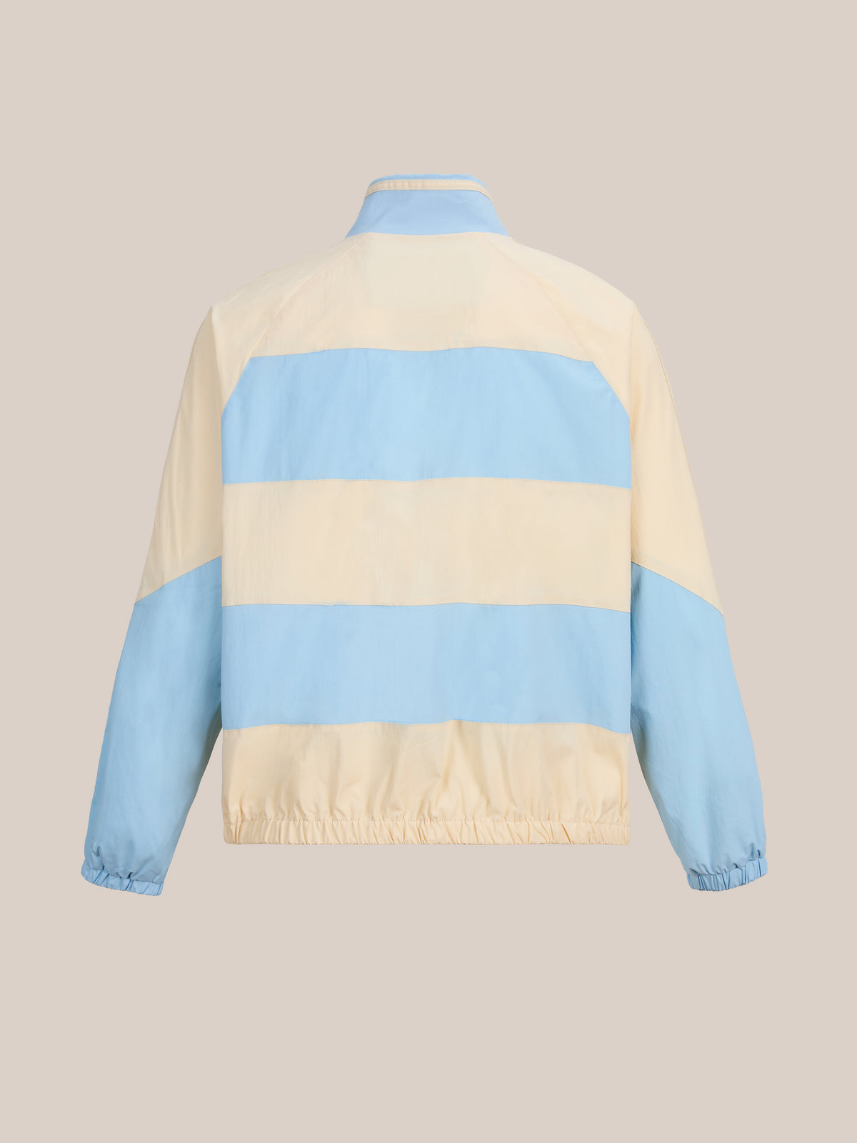 The FOUND Racing Striped Windbreaker is a unisex lightweight jacket with wide horizontal stripes in pastel blue and cream. It features long sleeves, elastic cuffs, and a straight collar, and is shown from the back against a plain background. This vintage sportswear piece seamlessly combines classic style with modern comfort.