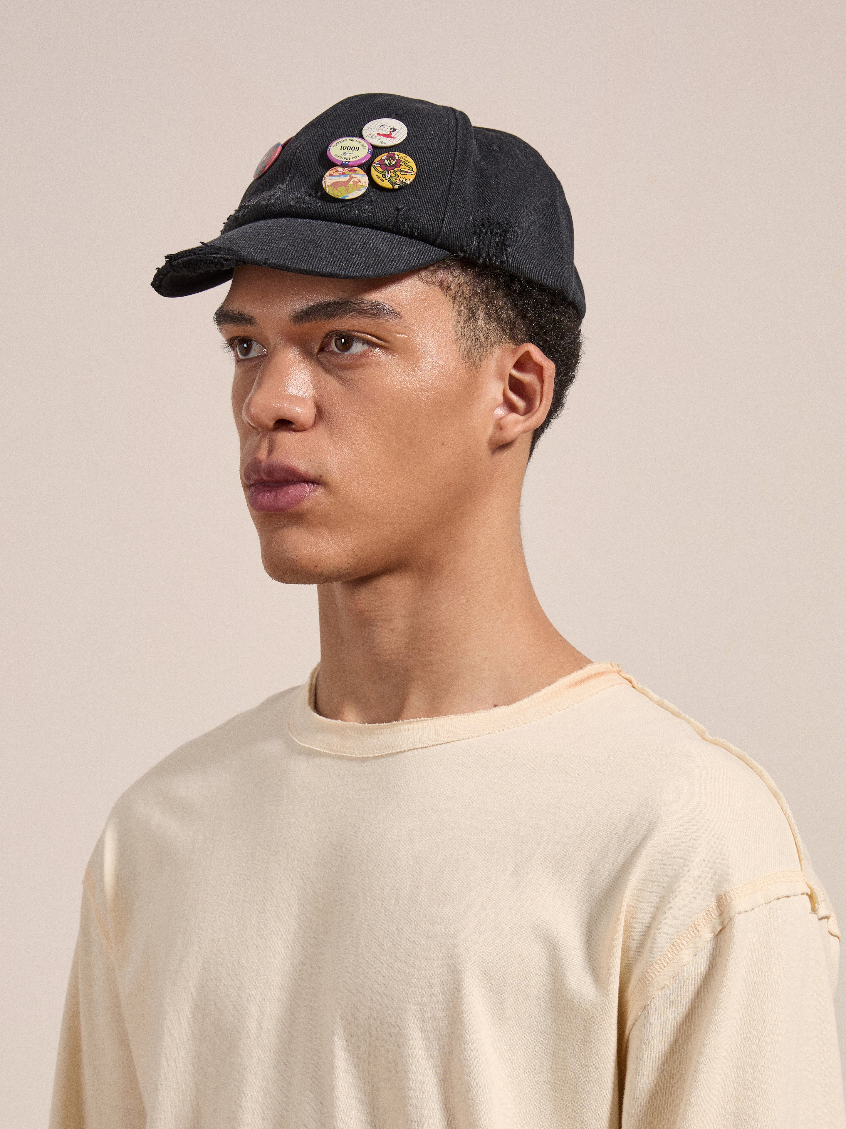A man wearing a FOUND Distressed Pin Cap and a beige t-shirt looks off to the side.