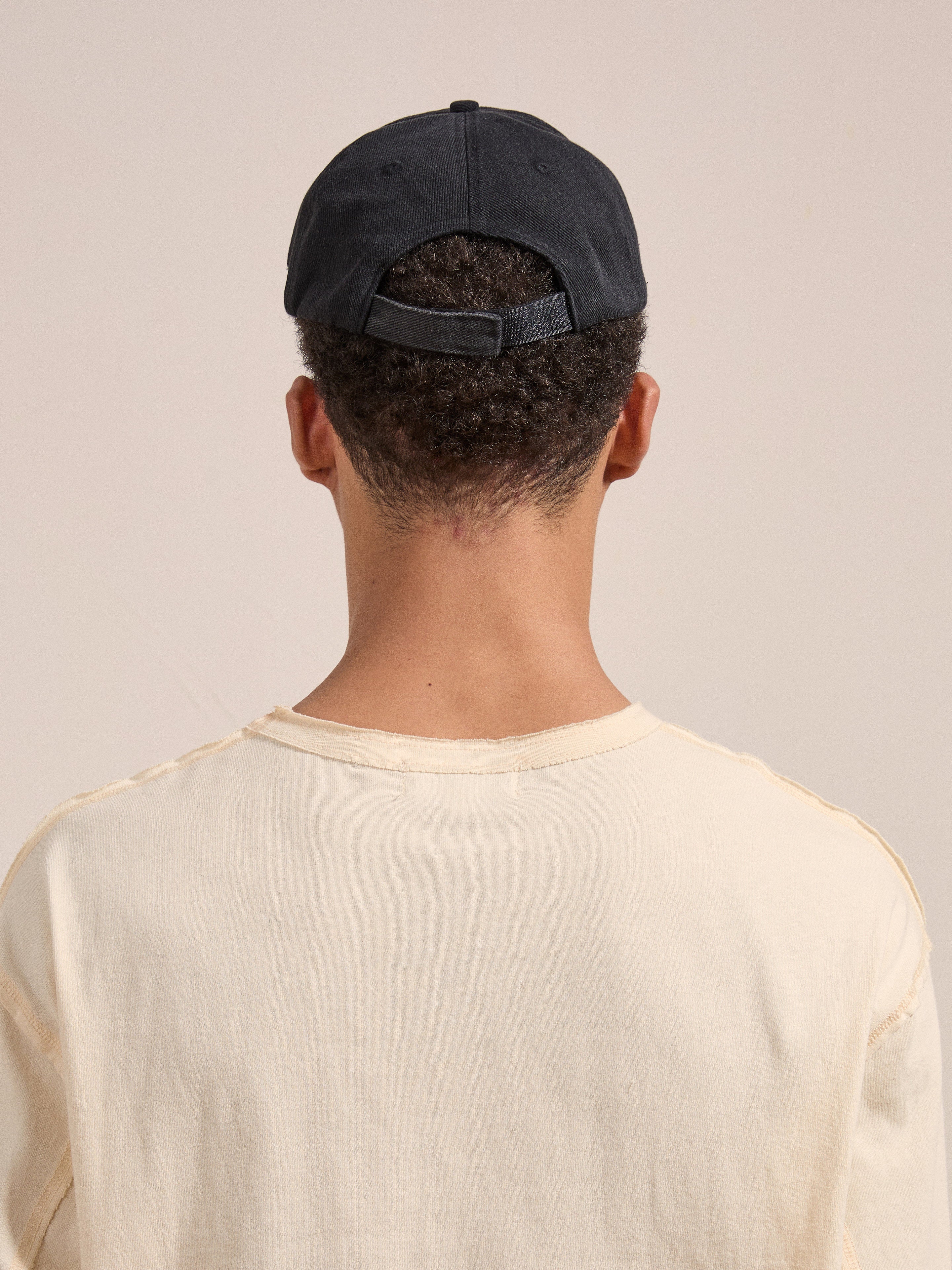 Rear view of a person with short hair wearing the FOUND Distressed Pin Cap and a light beige shirt.