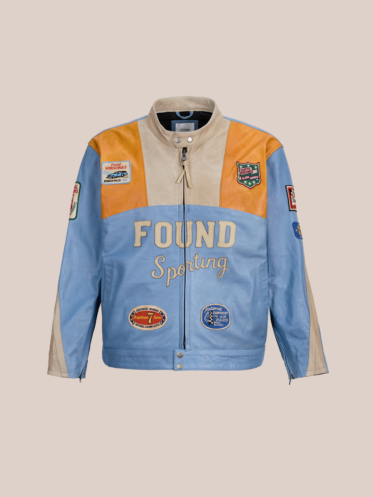 The FOUND Sport Racer Jacket features light blue, tan, and orange panels with “FOUND Sporting” lettering and racing patches on the front and sleeves.