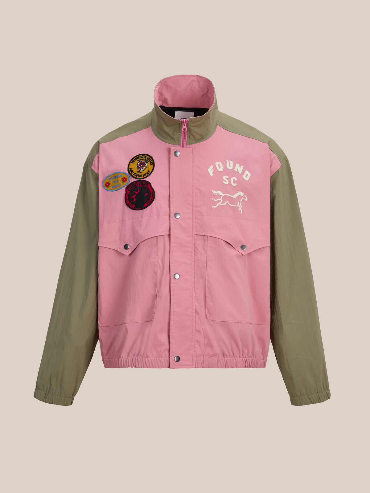 A vintage Sport Windbreaker Jacket by FOUND with a pink front, olive sleeves, embroidered patches, and a “FOUND SC” dog graphic on the left chest.