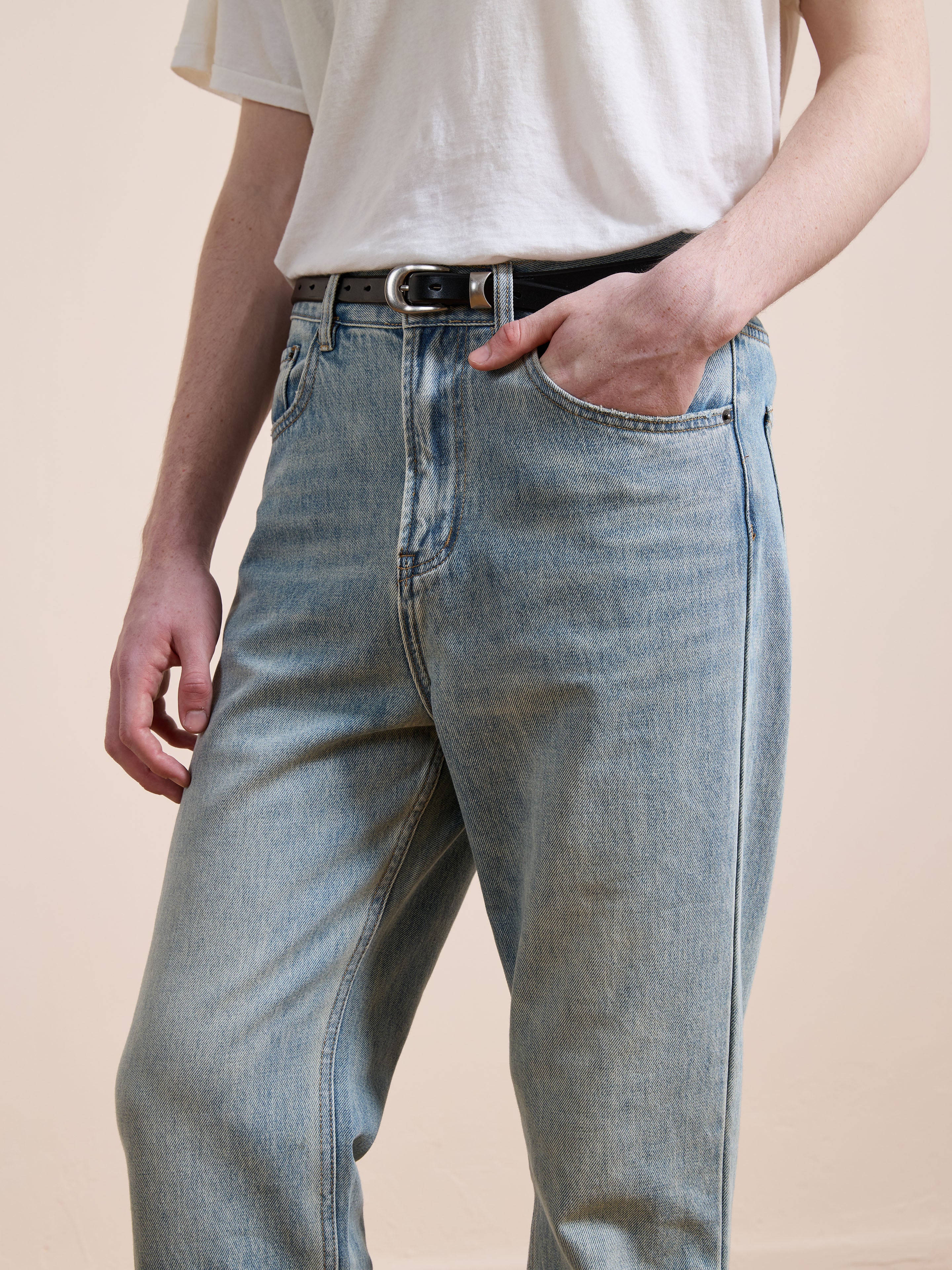 A person in Found Straight Leg Jeans and a white t-shirt, styled with a black belt and one hand in their pocket, stands against a neutral background.